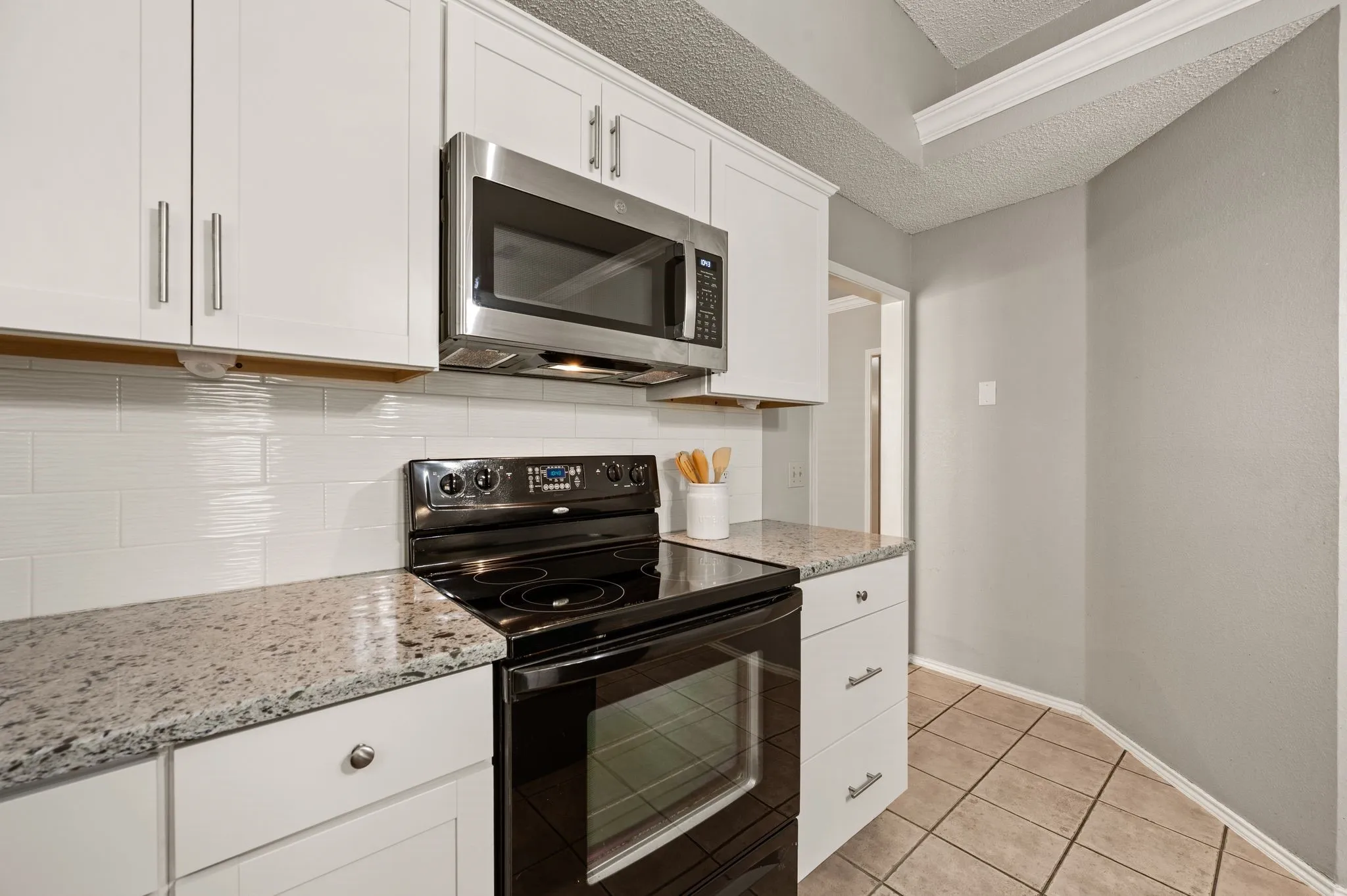 Sleek black appliances, granite countertops & a stylish tile backsplash complete the kitchen.