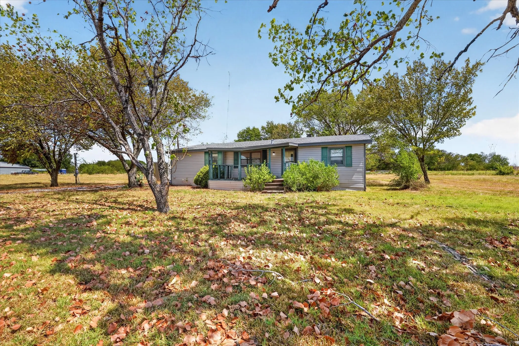 Single-story residence with light-colored siding, green shutters, and a covered porch entry
