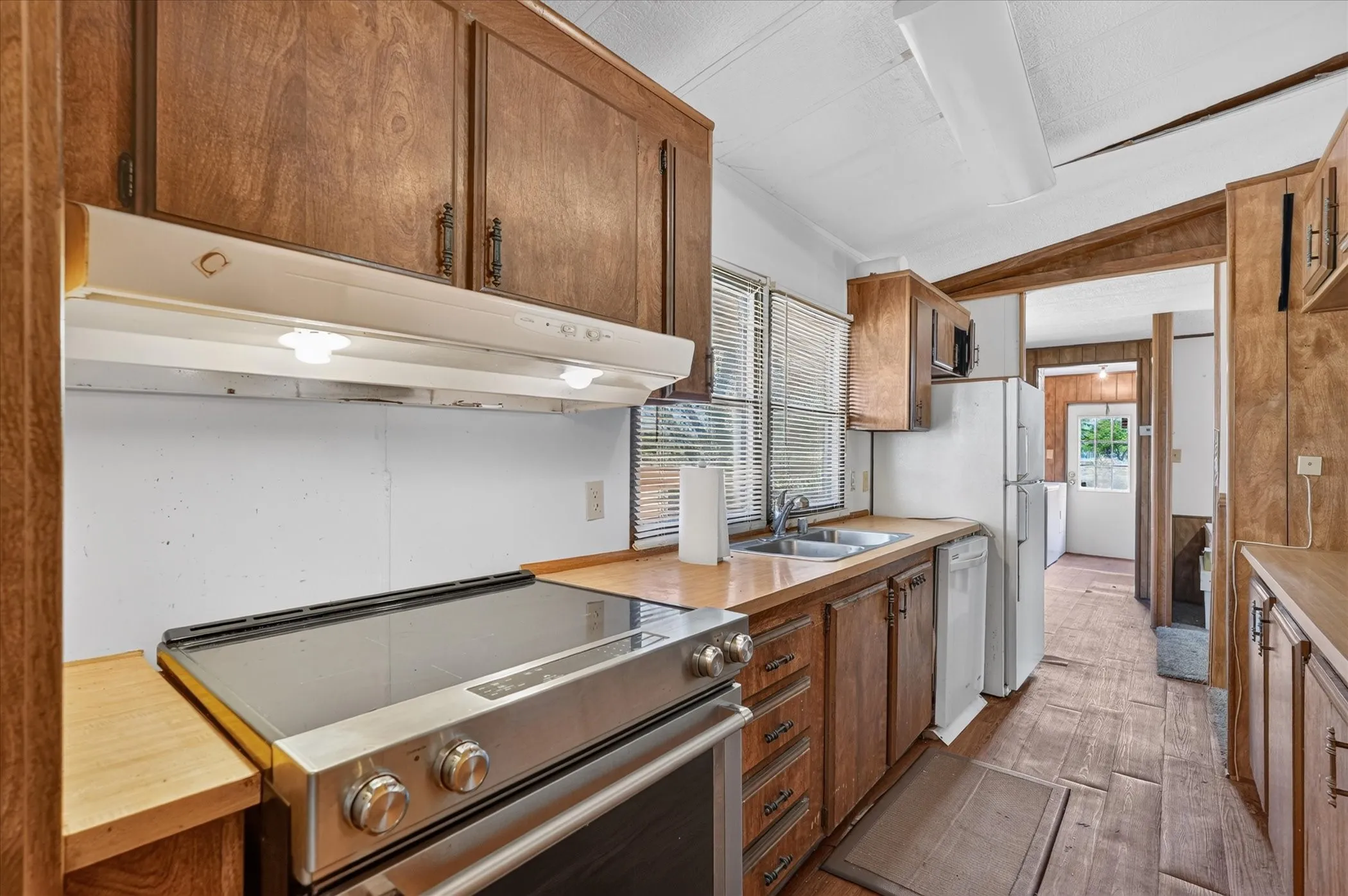 Kitchen featuring wood-finish cabinetry, stainless steel range, and wood-finish flooring