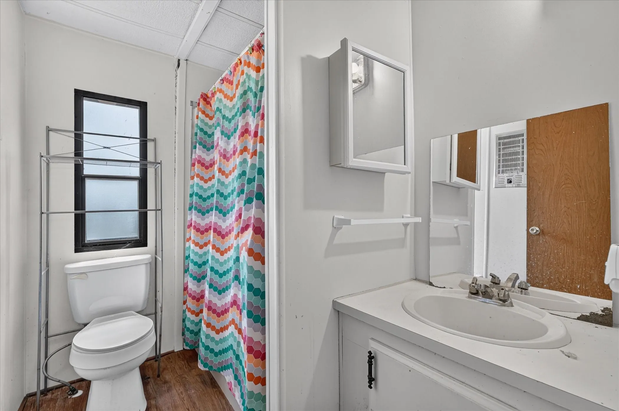 White wall paint, wood-finish flooring, and white vanity with an integrated sink