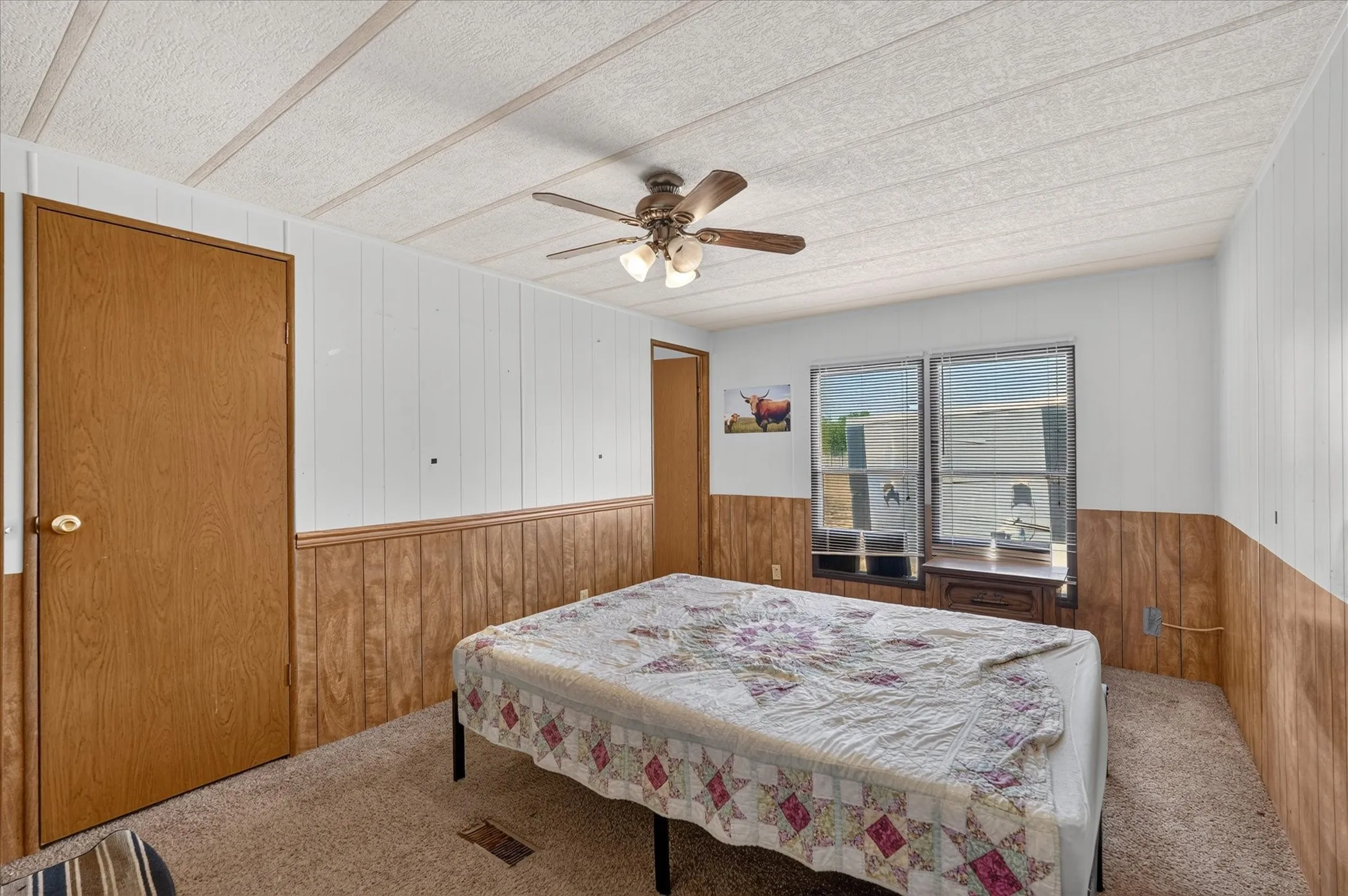 Carpeted flooring with wood-finish paneling and white paneled walls