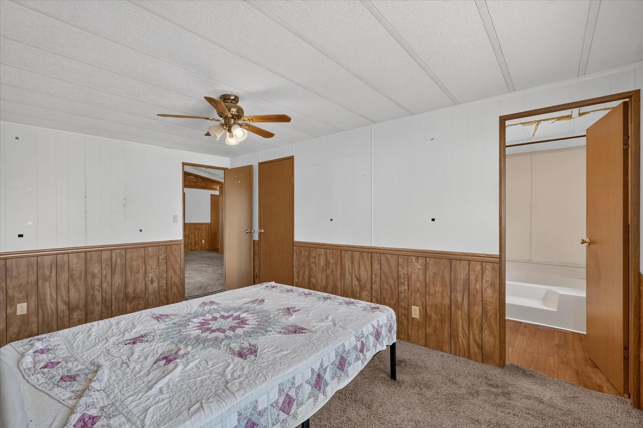 Carpeted flooring, wood-panel wainscoting, and a ceiling fan