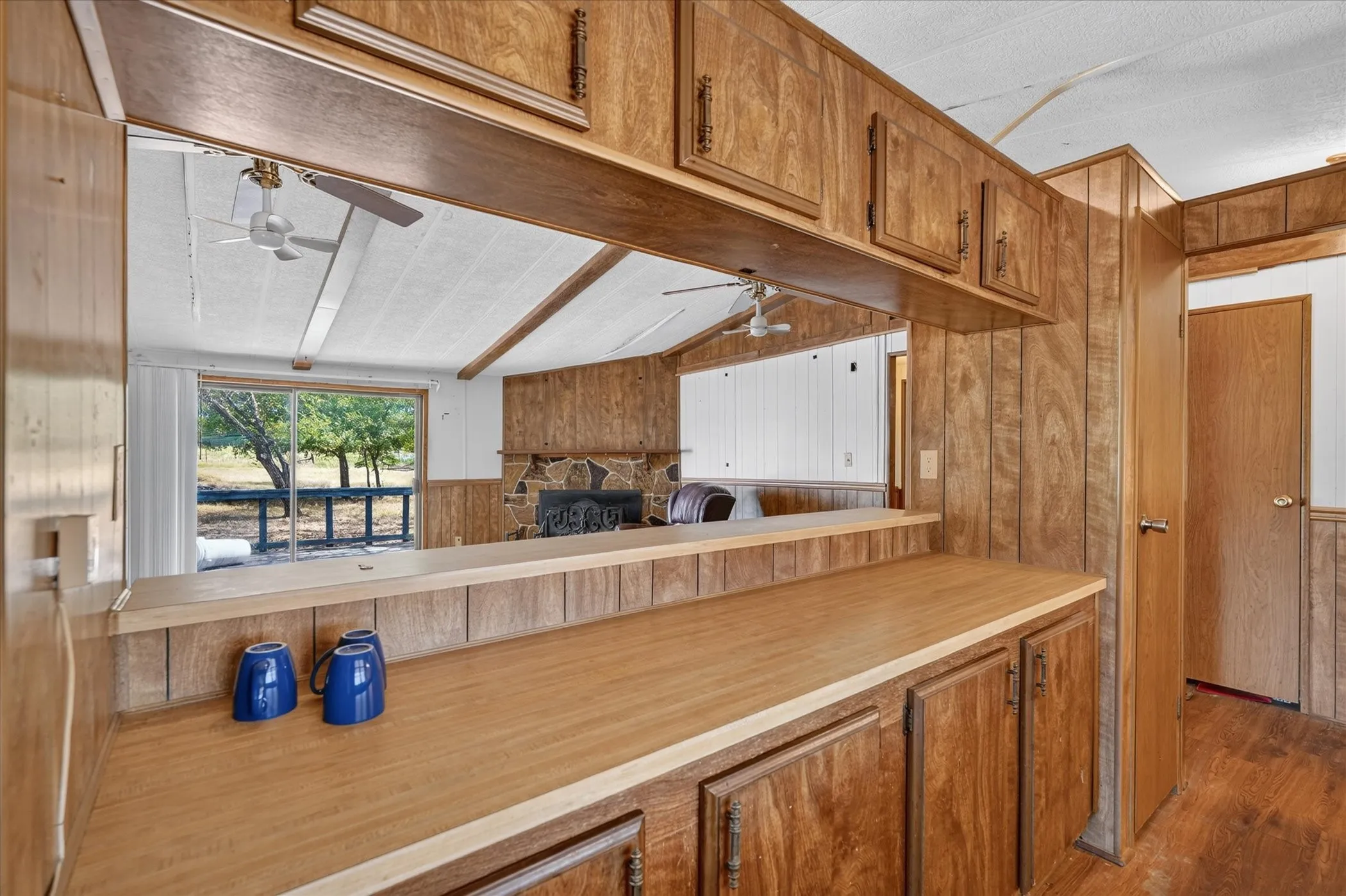 Wood-finish cabinetry and paneling throughout, featuring a pass-through window with a wood-finish countertop