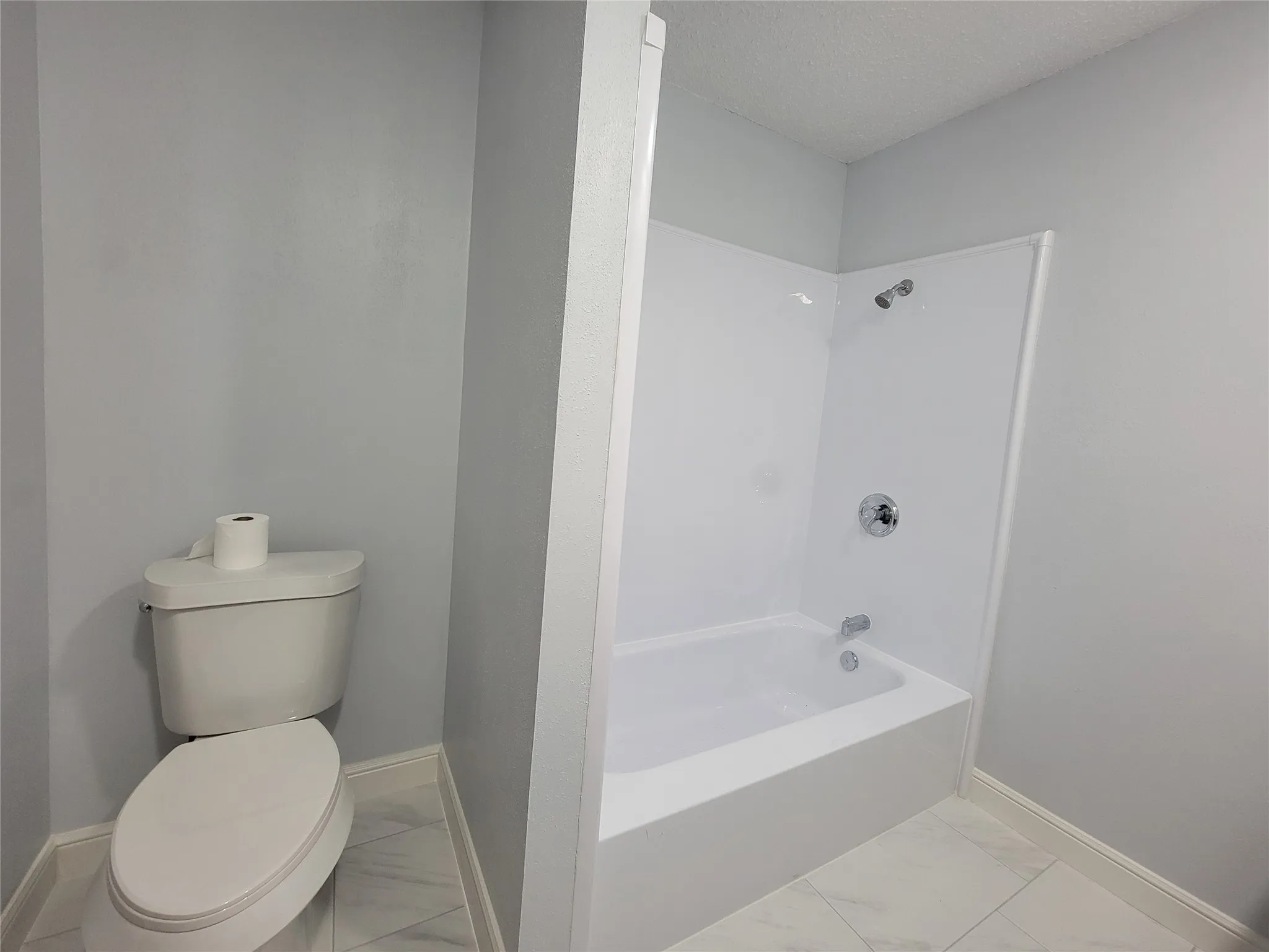 White paneled tub and shower combination with chrome fixtures