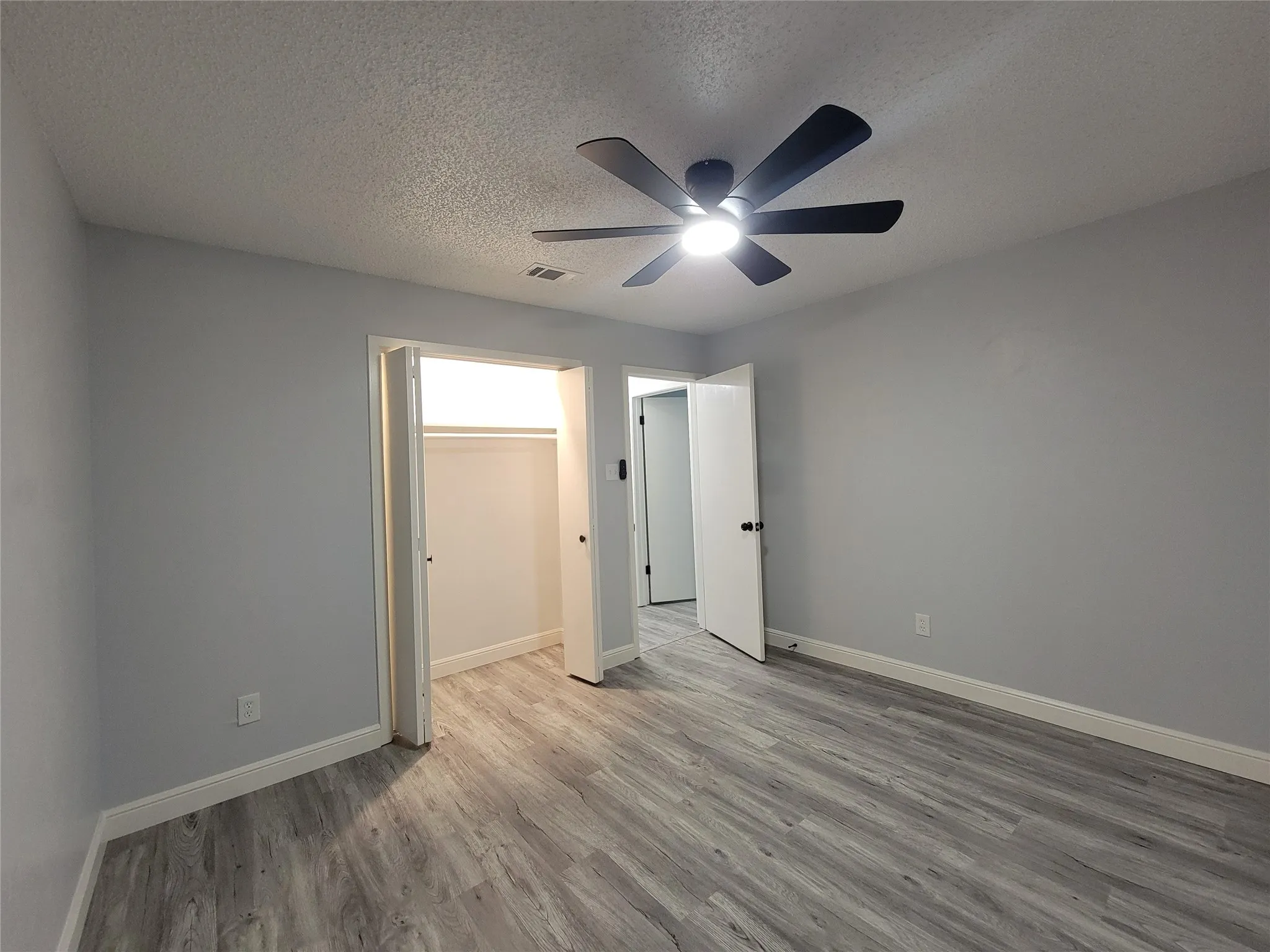 Wood-finish flooring, ceiling fan with integrated lighting, and a closet with bi-fold doors
