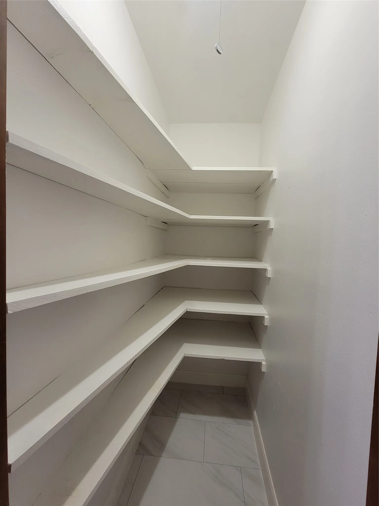 Built-in shelving with multiple levels, white finishes, and a tiled floor