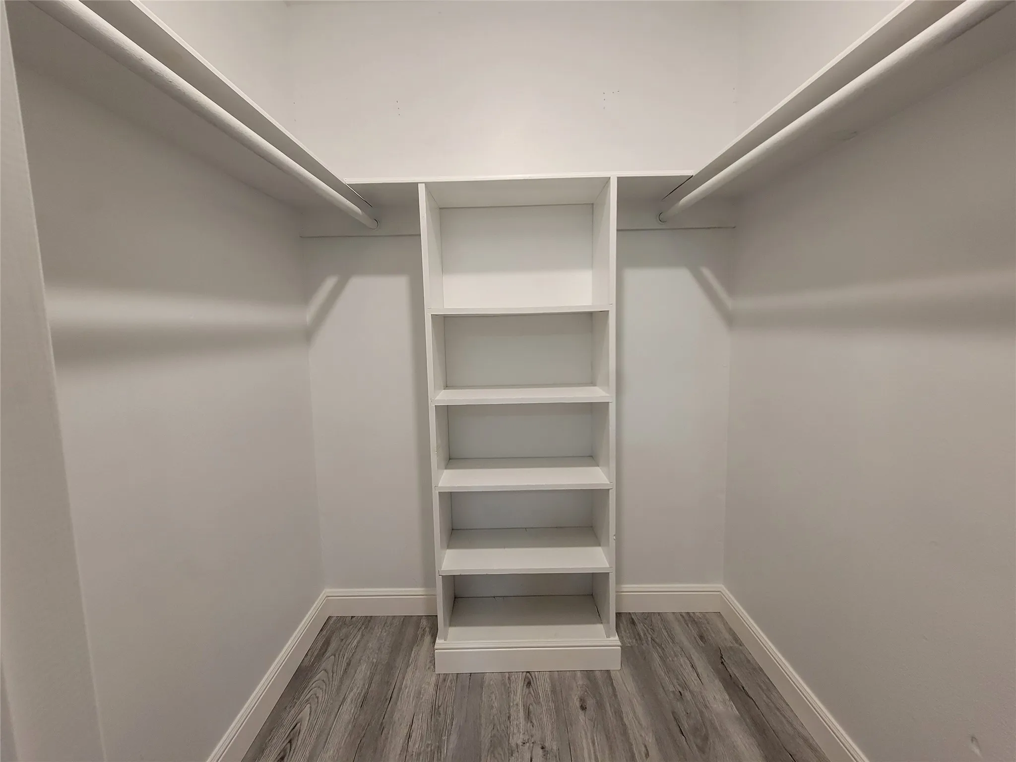 Built-in shelving unit, dual hanging rods, wood-finish flooring, white wall finish, white trim