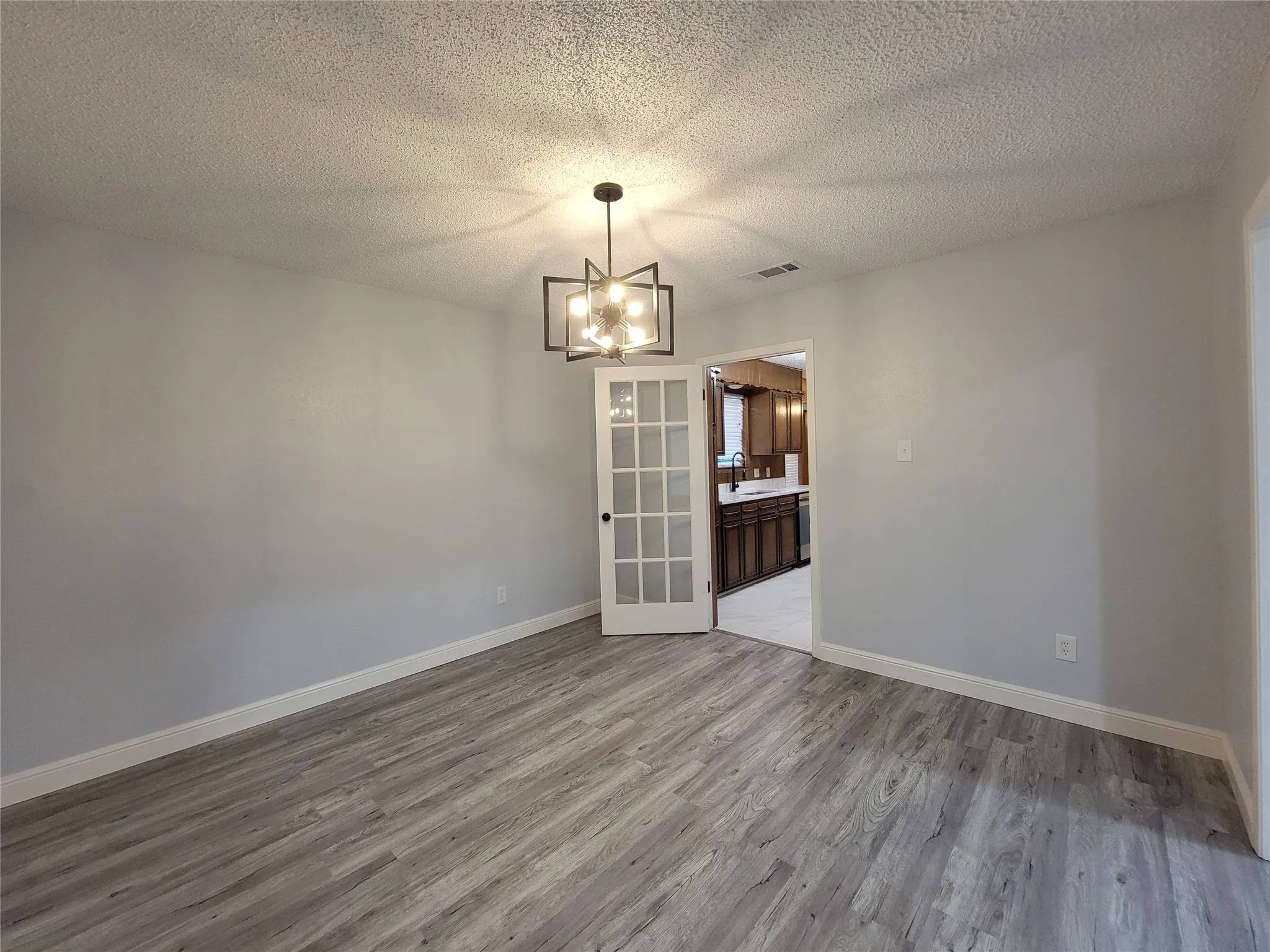 Wood-finish flooring, white baseboards, and a modern geometric chandelier
