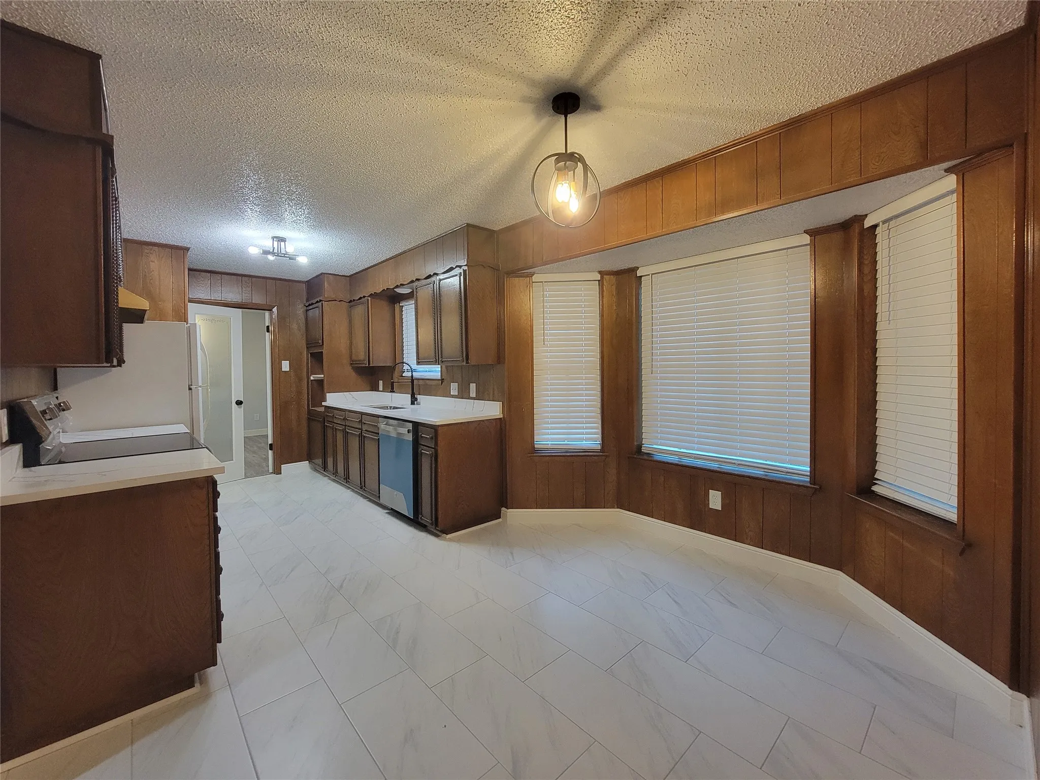 Kitchen with wood-finish cabinetry, light-toned countertops, and a stainless steel dishwasher