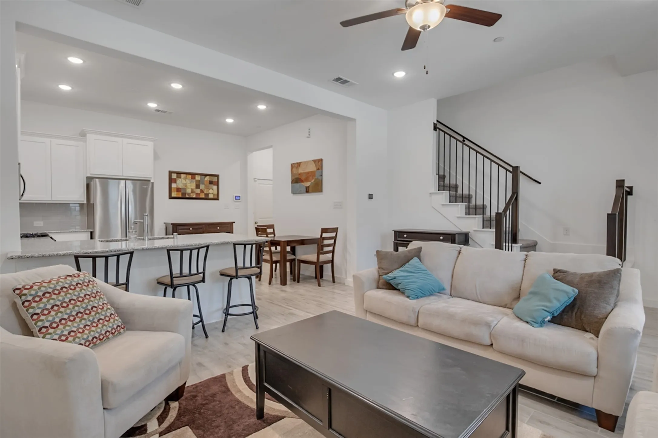 Open-concept living area with wood-finish flooring, recessed lighting, and a ceiling fan