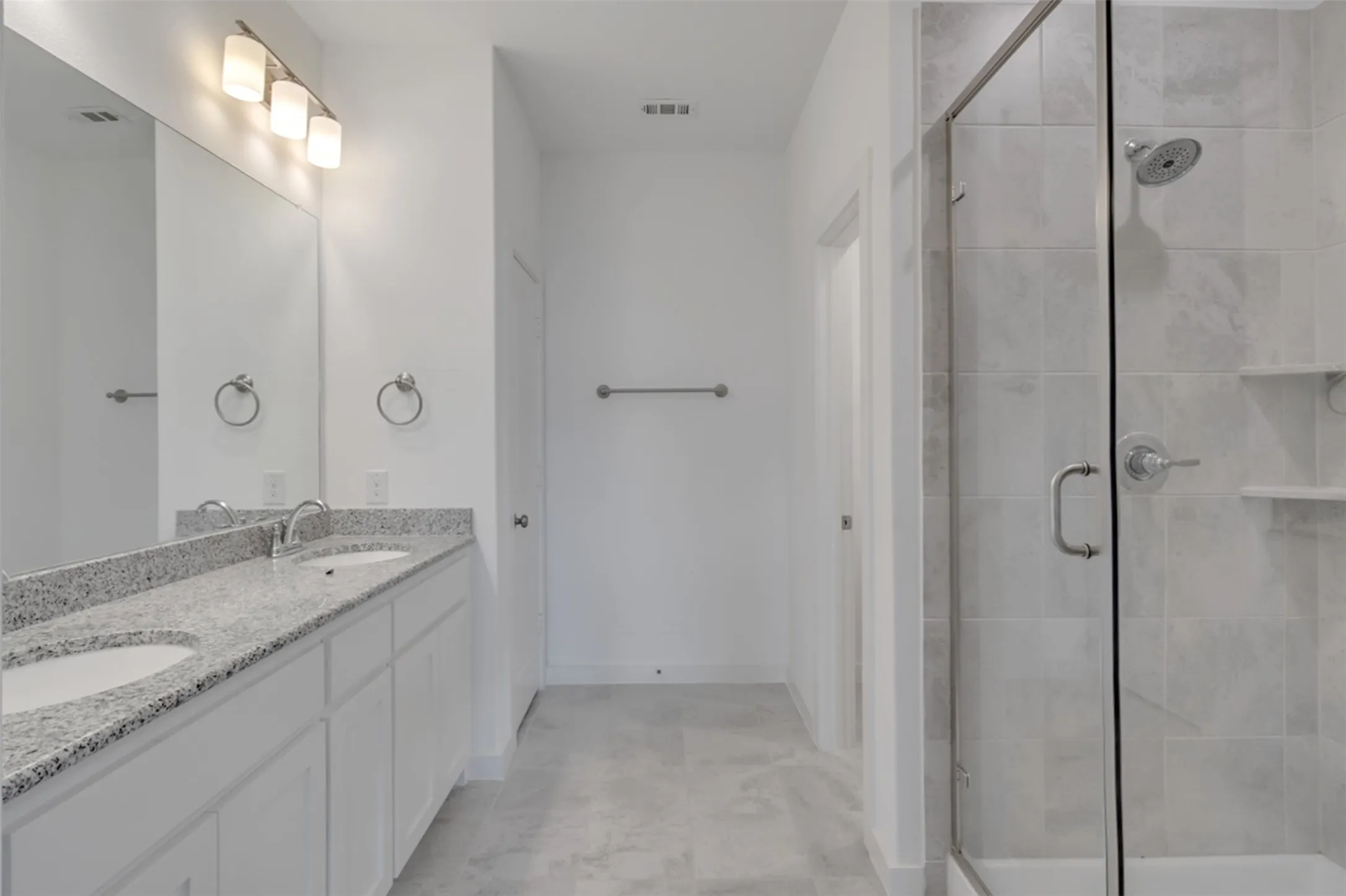 Dual vanity with granite countertop, individual sinks, and overhead bar lighting