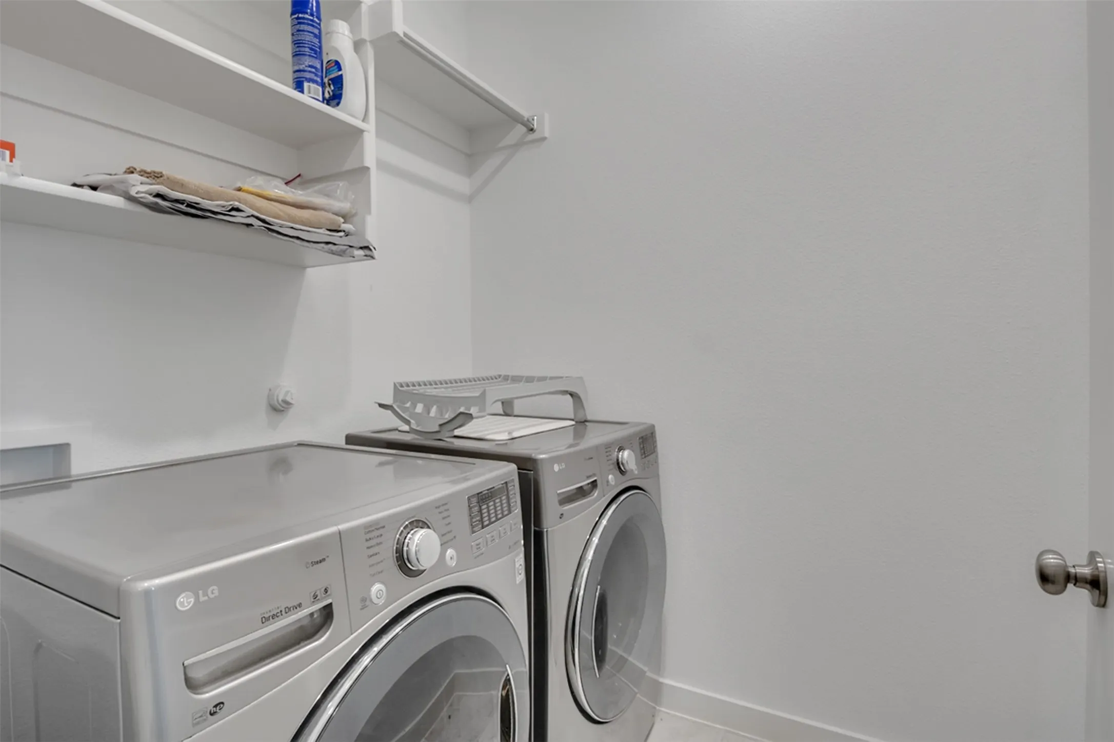 Laundry area featuring wall-mounted shelving and a clothing rod