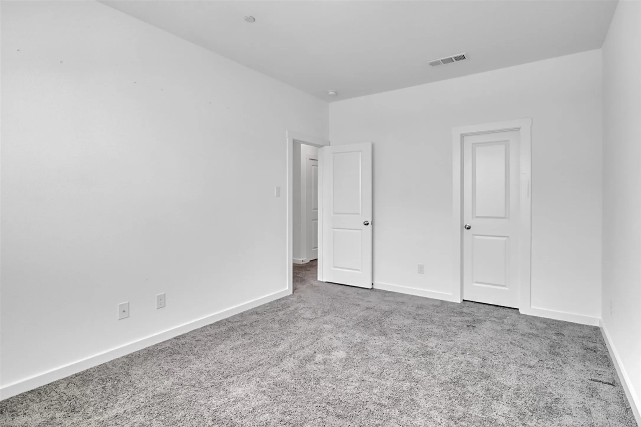 Neutral wall finishes, recessed ceiling lighting, two-panel interior doors, and textured carpeting