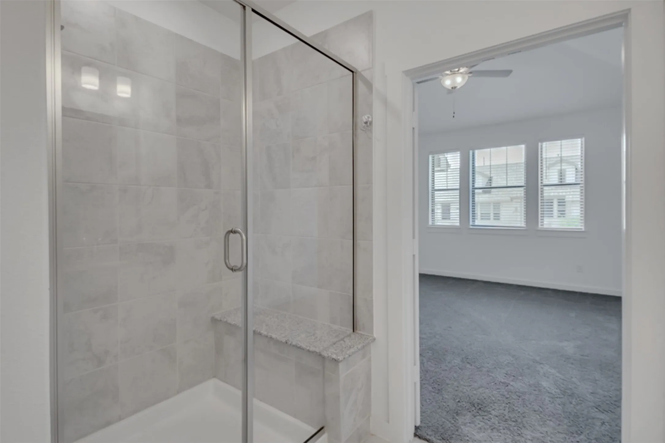 Walk-in shower with tiled surround, frameless glass enclosure, built-in bench, and overhead lighting