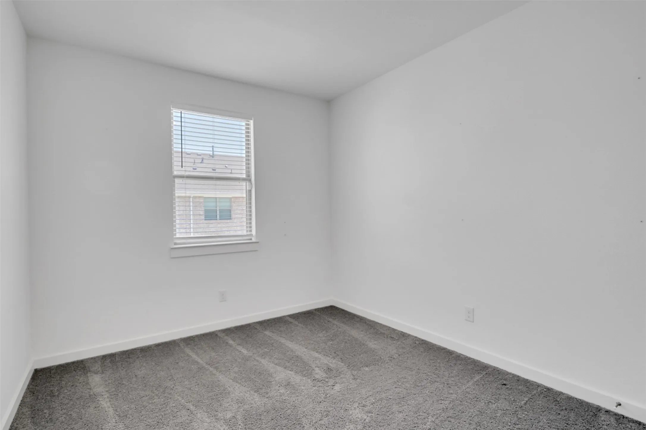 Neutral wall color with a single window featuring horizontal blinds