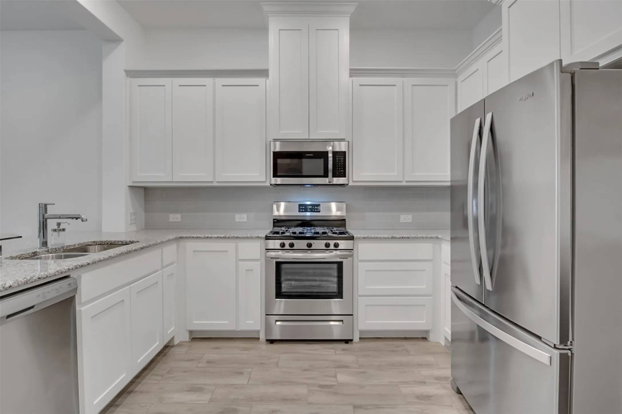 Kitchen featuring white shaker cabinetry, stainless steel appliances, granite countertops, and wood-finish flooring