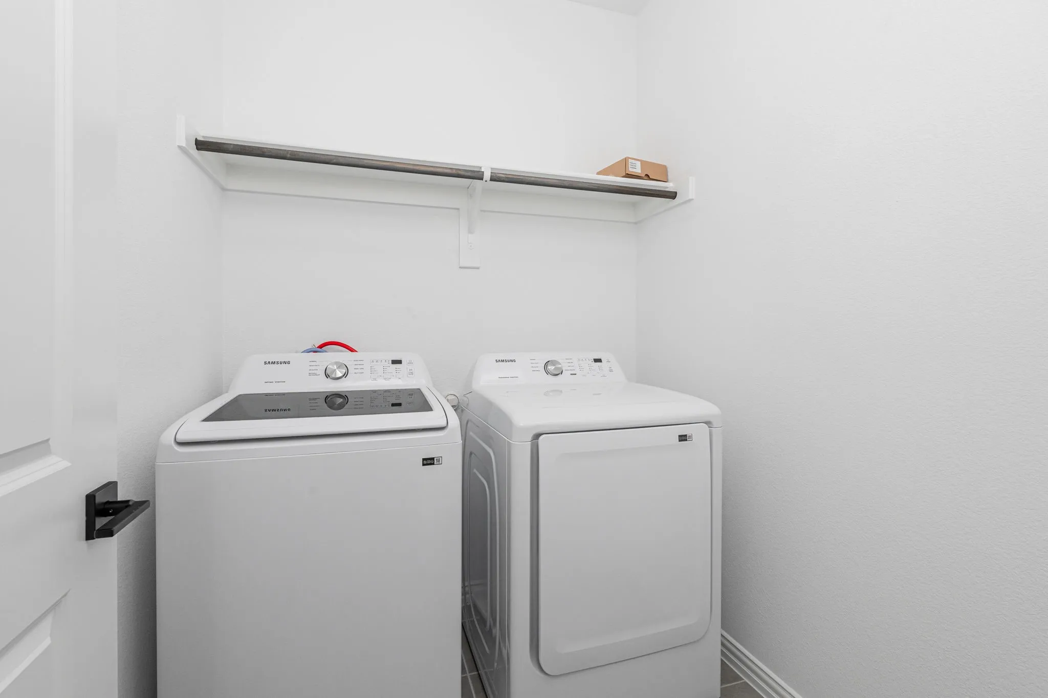 Convenient 2nd floor laundry room features a full-size washer and dryer, built-in overhead shelving, and a functional layout designed to keep laundry essentials organized and easily accessible.