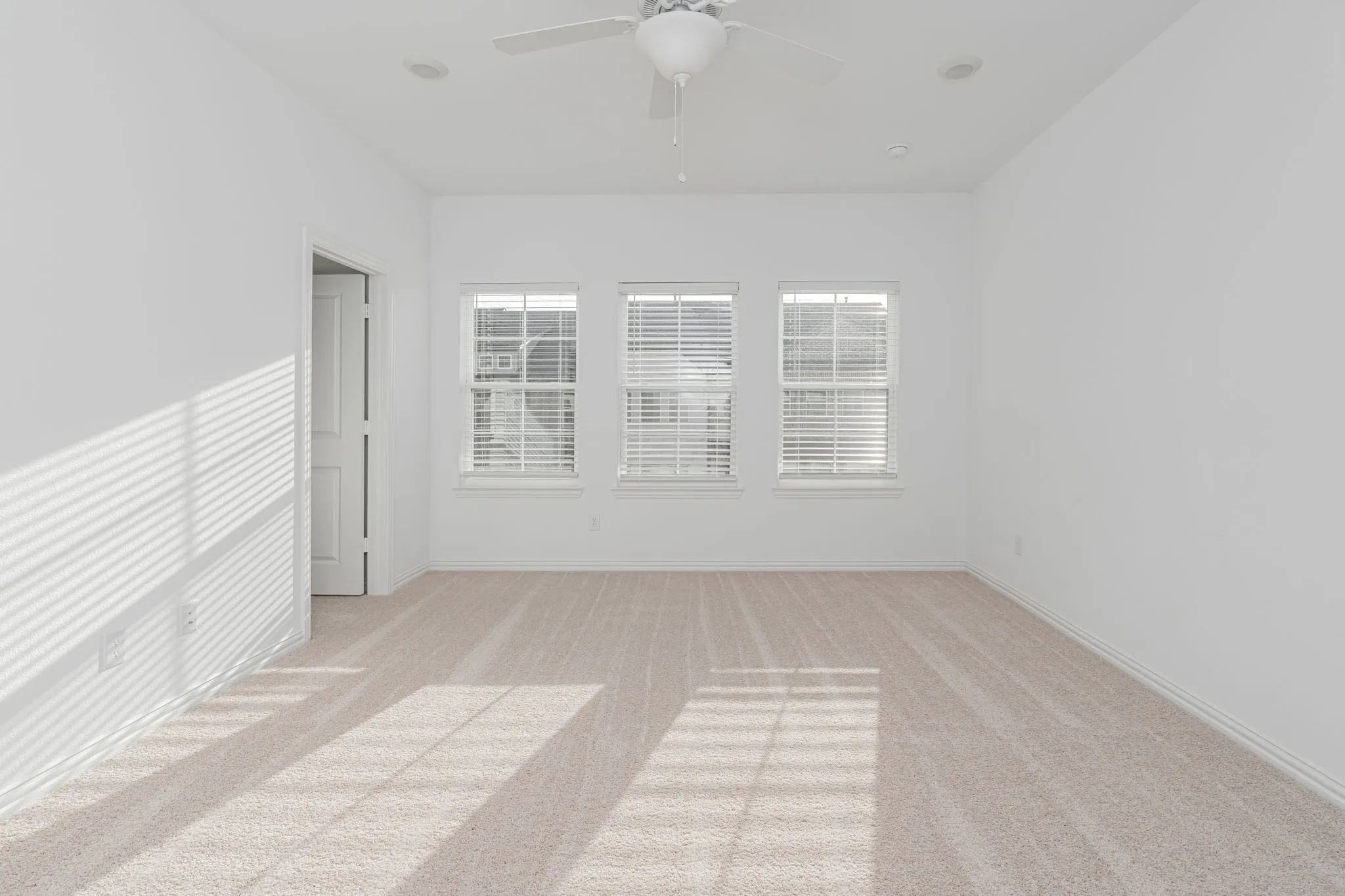Generously sized upstairs primary bedroom featuring three windows, plush carpeting, a ceiling fan, and an abundance of natural light—an inviting retreat!