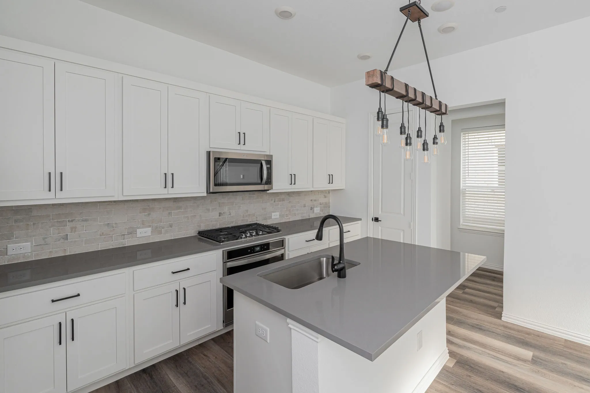 Chef-inspired kitchen highlighted by extensive cabinetry and counter space, stainless-steel appliances, gas range, modern finishes, and a large island that provides an ideal gathering and prep space.