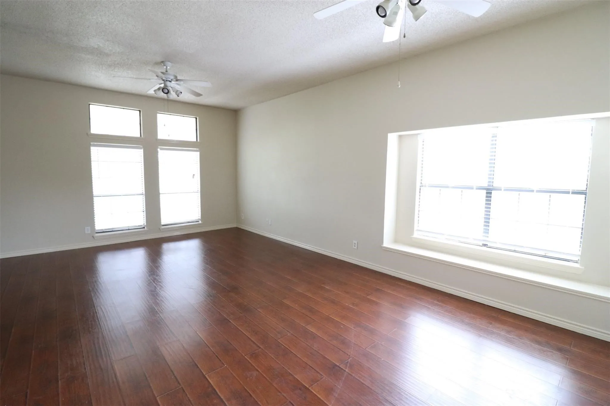 Vaulted ceiling, wood-finish flooring, multiple windows, window seat, and ceiling fans