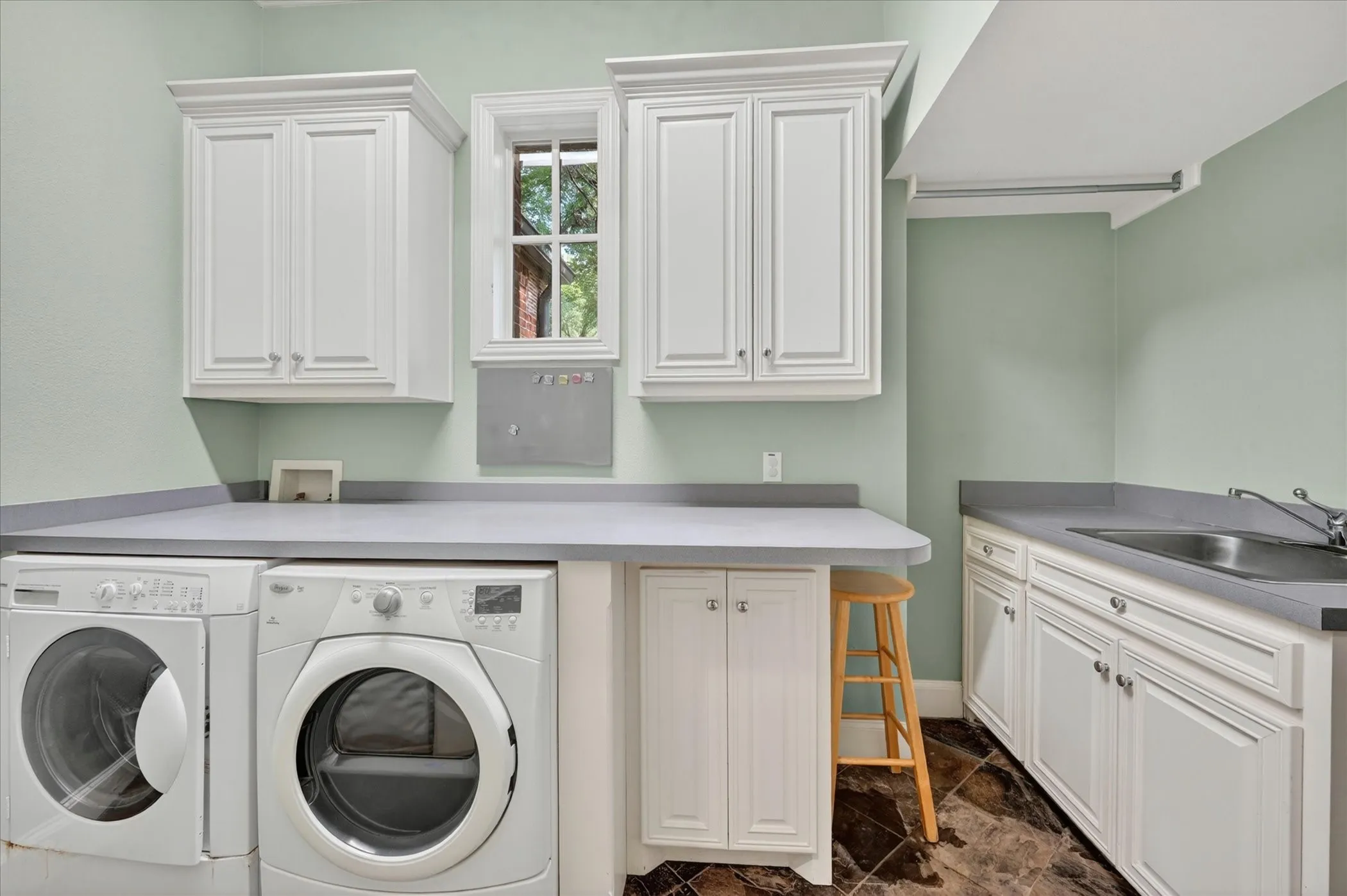 Laundry room with built-in cabinets, sink, and counters for folding.
