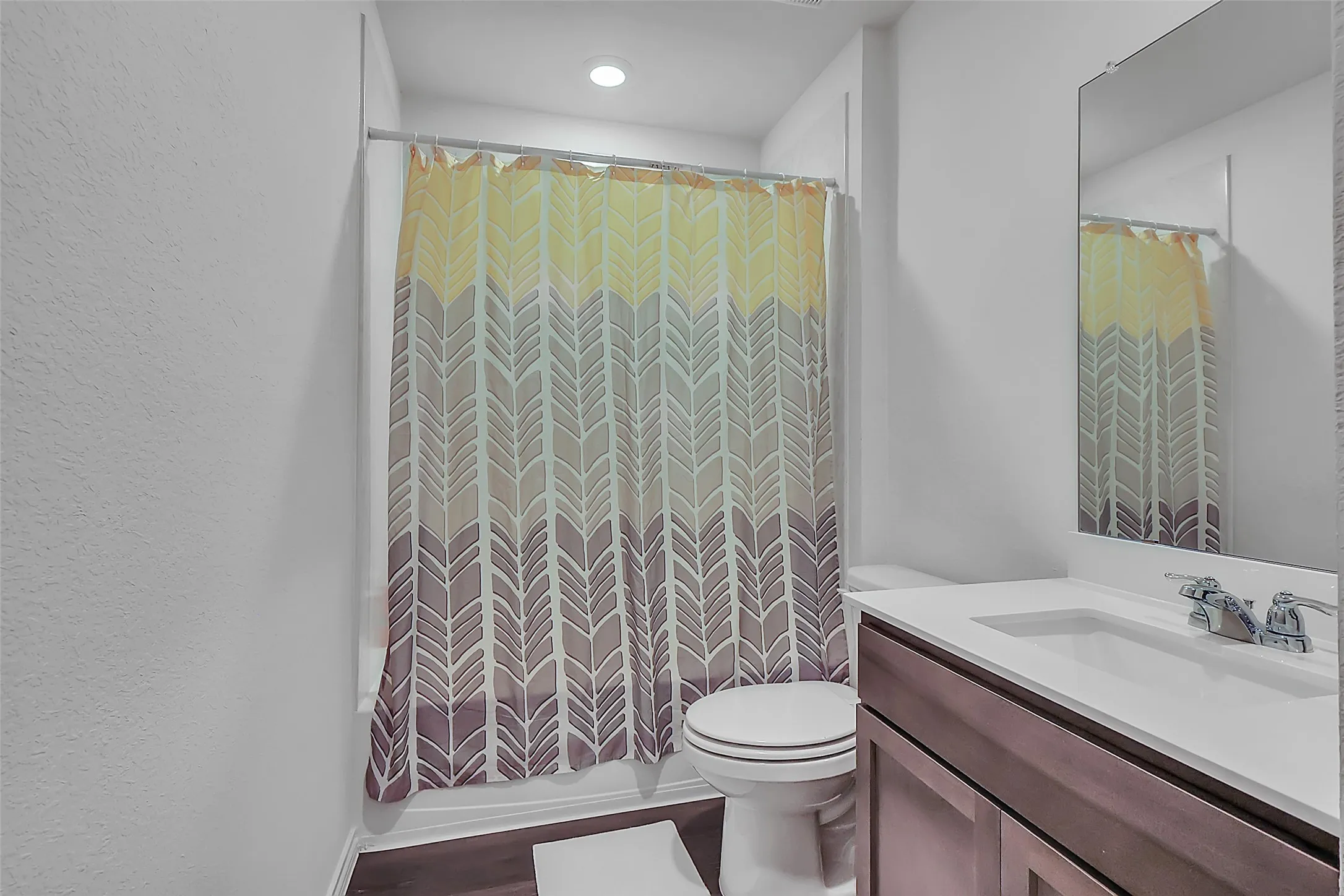 Contemporary bathroom featuring a built-in vanity with a white countertop and undermount sink, brushed nickel faucet, wall-mounted mirror, and wood-finish flooring