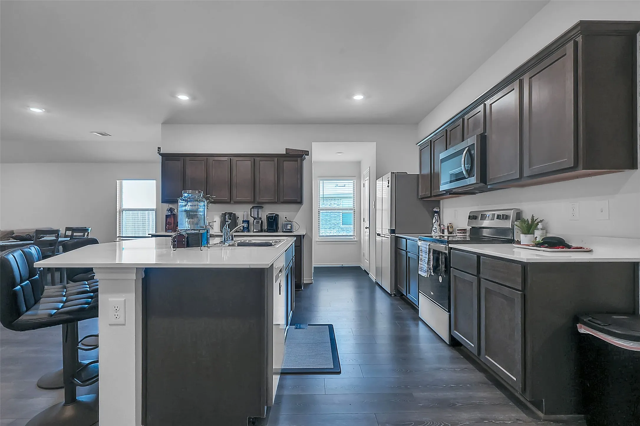 Kitchen featuring a center island, dark wood-finish cabinetry, stainless steel appliances, and wood-finish flooring