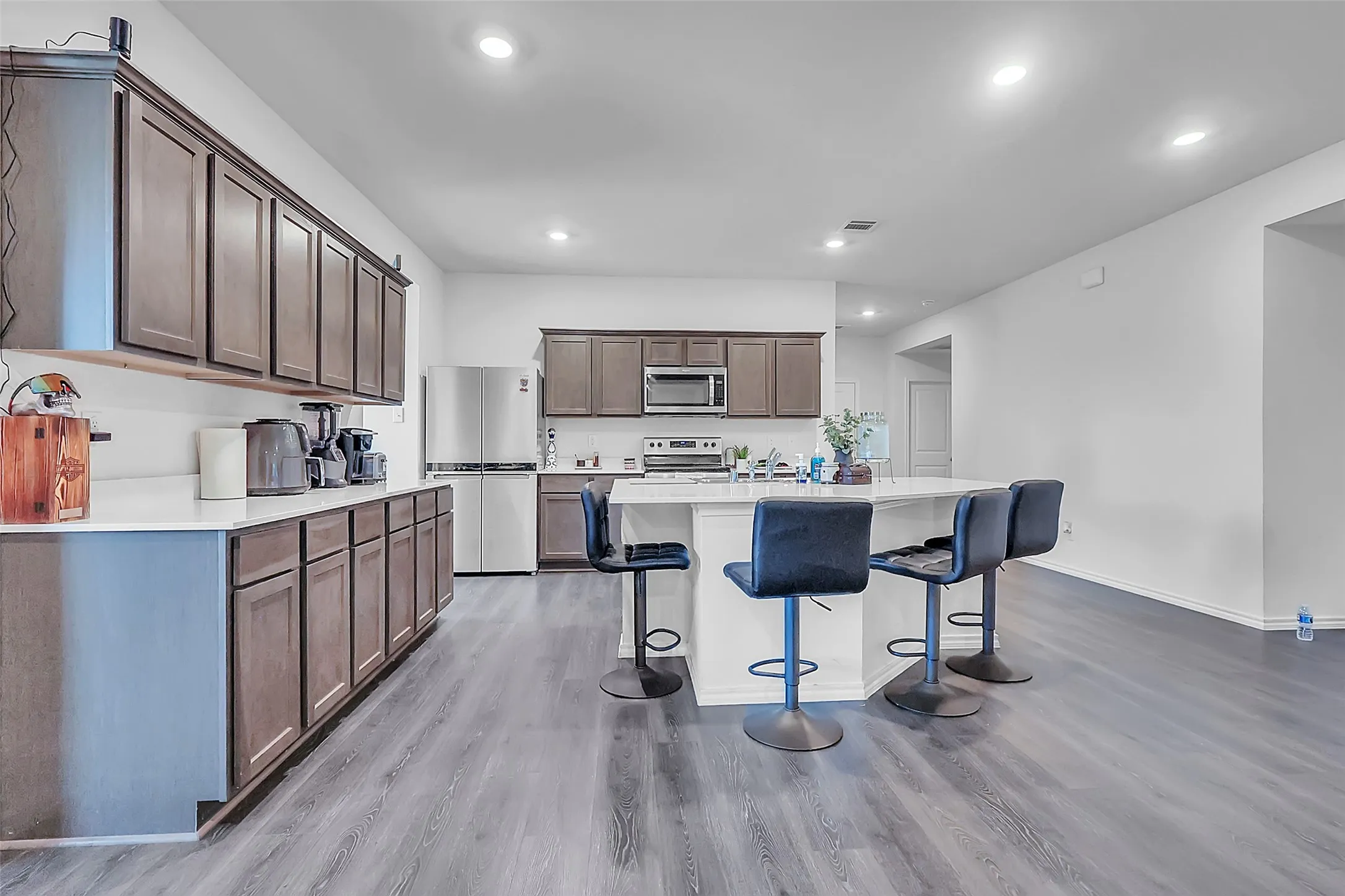 Spacious kitchen featuring an island with seating, extensive cabinetry with dark wood-finish fronts, and stainless steel appliances
