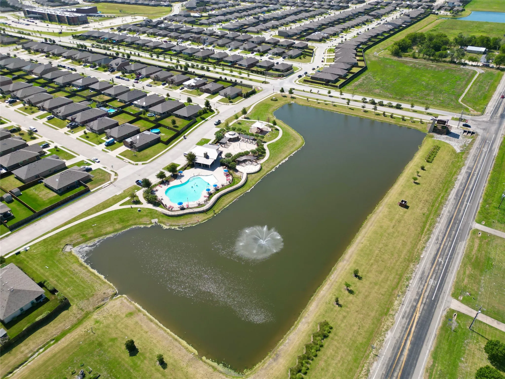 Community amenities featuring a swimming pool, shaded seating areas, and a central pond with a fountain