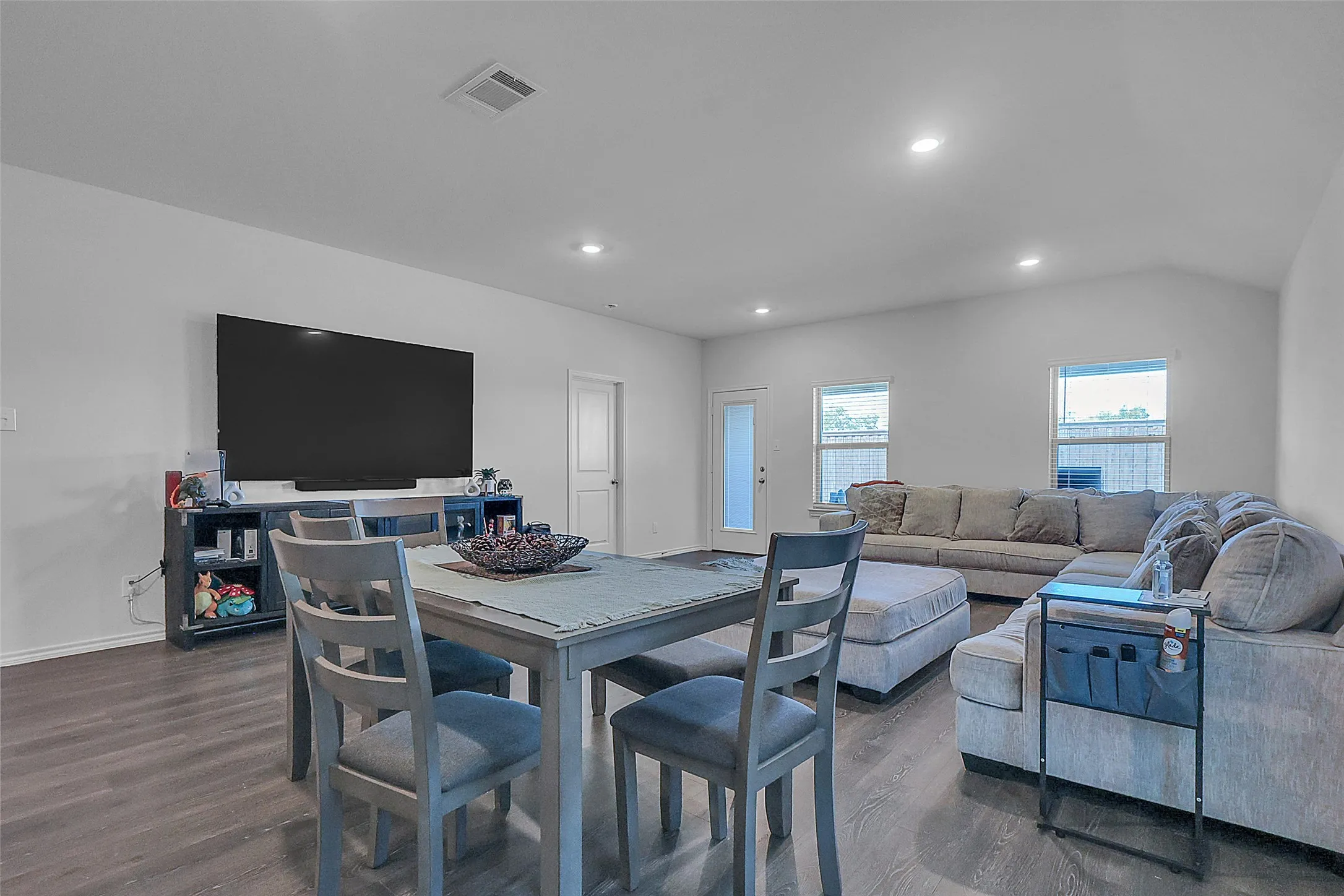Open-concept living area with wood-finish flooring, recessed lighting, and white walls