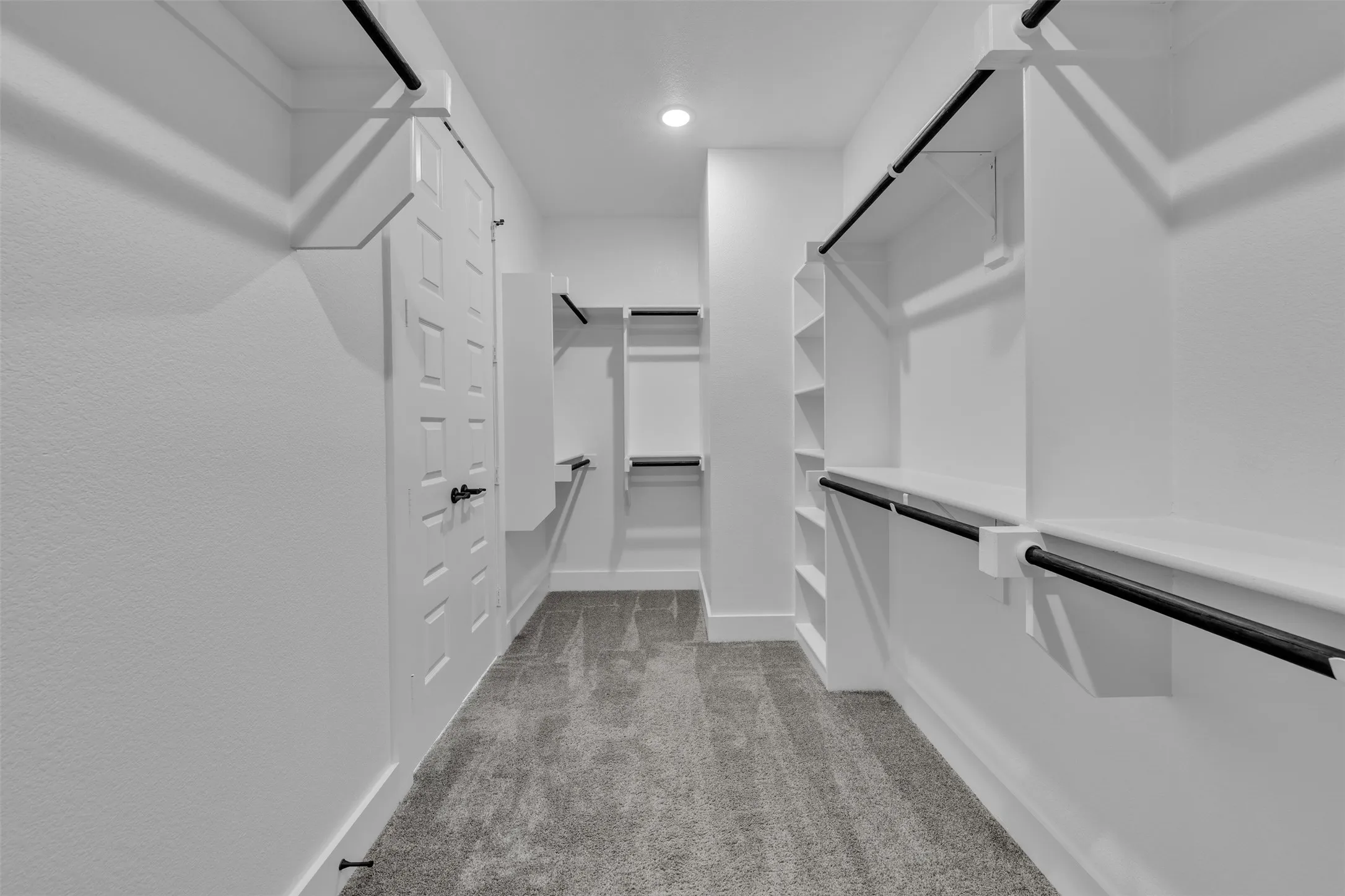 Walk-in closet with carpet flooring, recessed lighting, white built-in shelving, and black hanging rods
