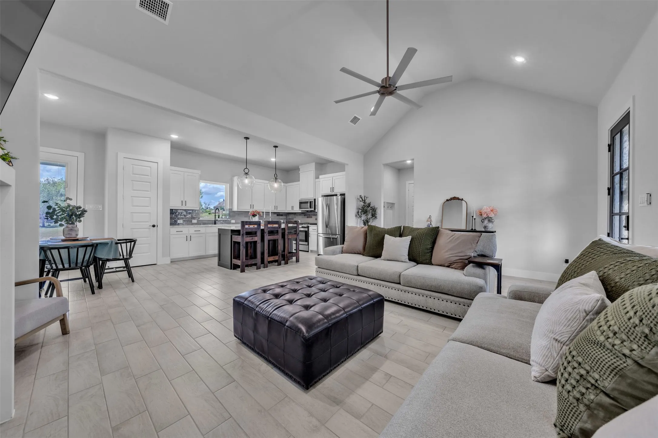Vaulted ceiling with a contemporary ceiling fan, recessed lighting, wood-finish flooring, kitchen island with seating, and stainless steel appliances