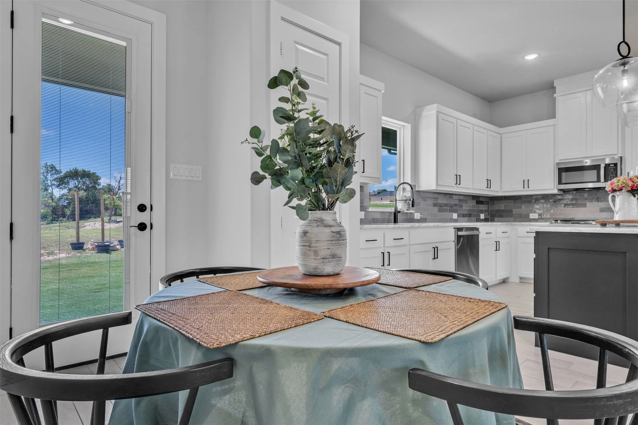 White shaker-style cabinetry with dark hardware, stainless steel appliances, and a gray tile backsplash