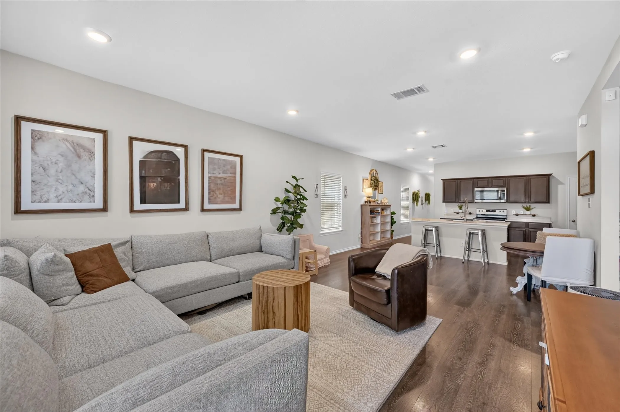Open-concept living space with recessed lighting, wood-finish flooring, and a kitchen island with seating