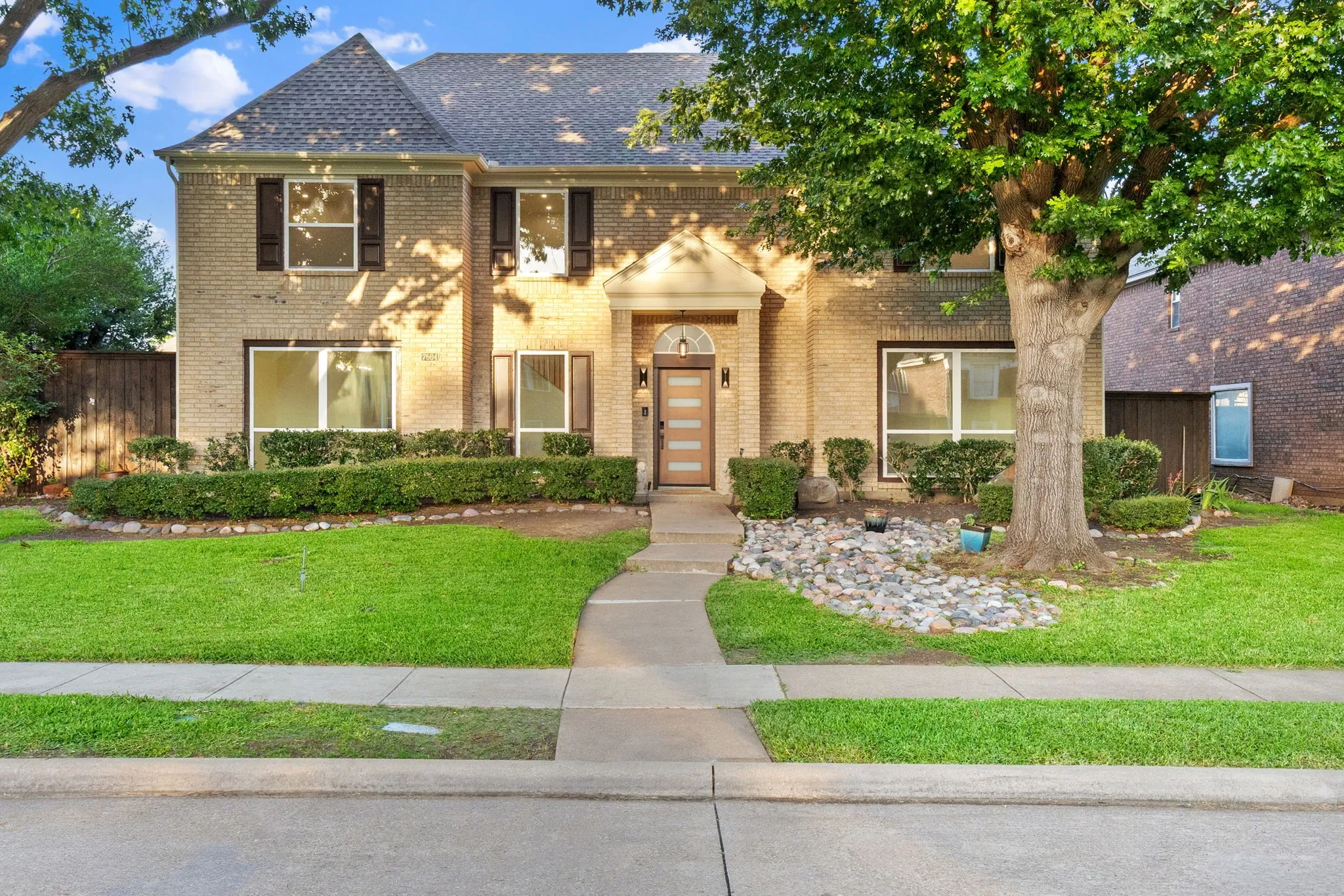 Traditional brick facade residence featuring a prominent entryway, dark-shingle roof, and decorative window shutters