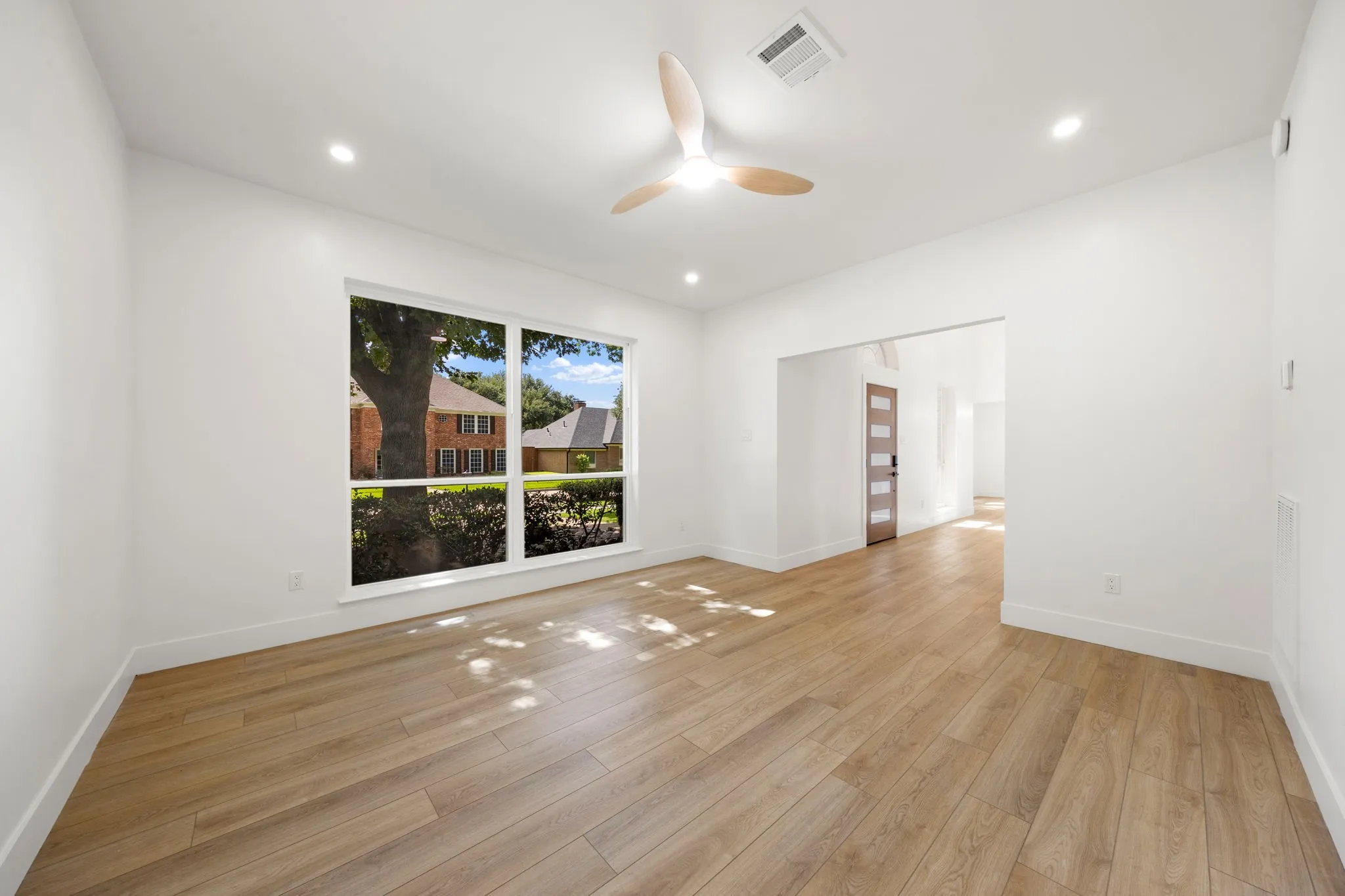 Bright interior space featuring a large window, recessed lighting, and wood-finish flooring
