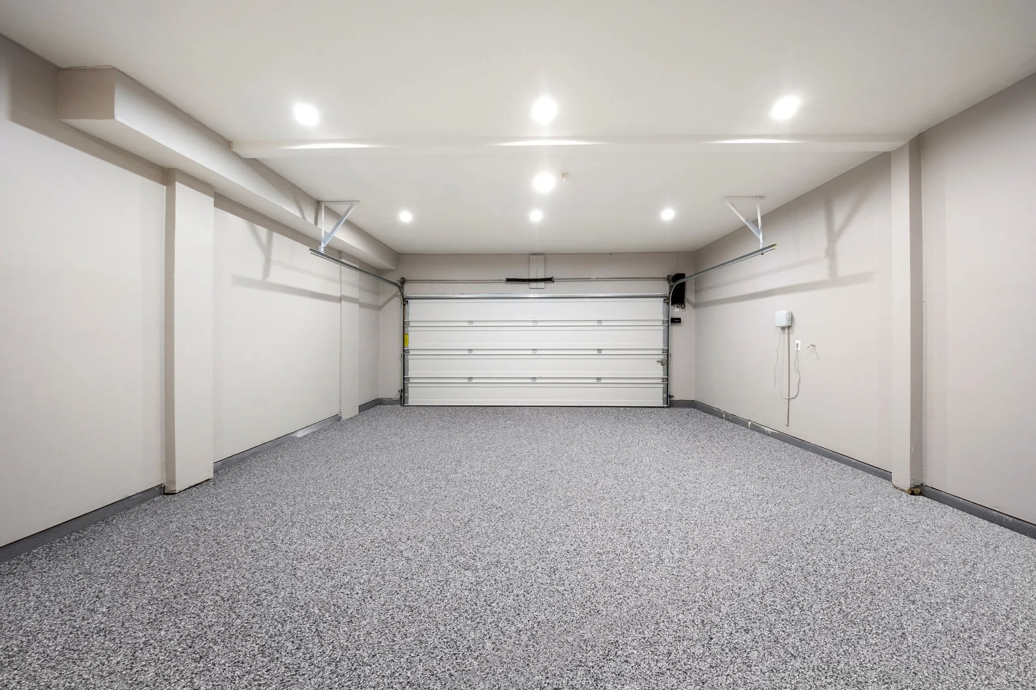Spacious garage featuring a speckled epoxy floor, recessed ceiling lighting, a panel garage door, and light neutral wall tones
