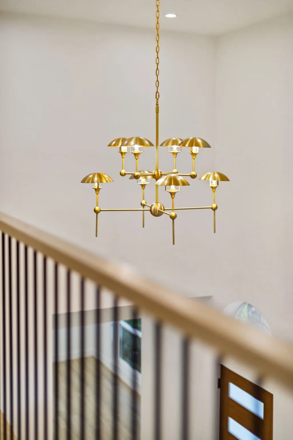 Contemporary brass chandelier with multiple lights, suspended from a high ceiling