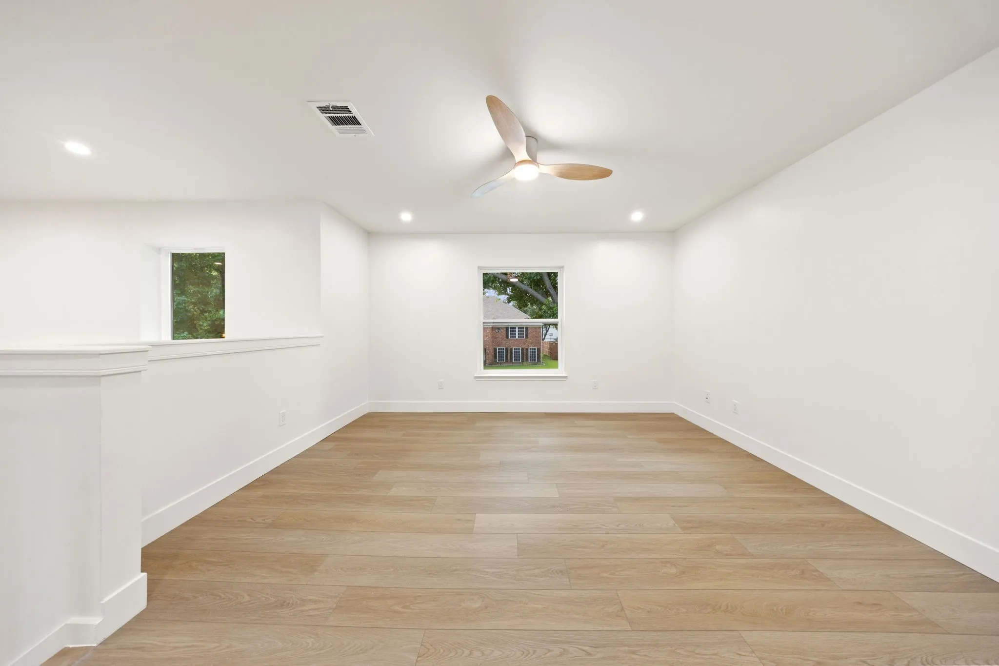 Spacious room featuring wood-finish flooring, recessed lighting, and a contemporary ceiling fan