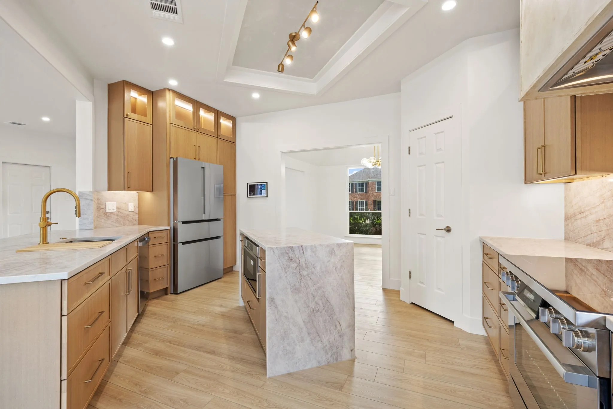 Modern kitchen featuring light wood-finish cabinetry, stainless steel appliances, and light-toned countertops