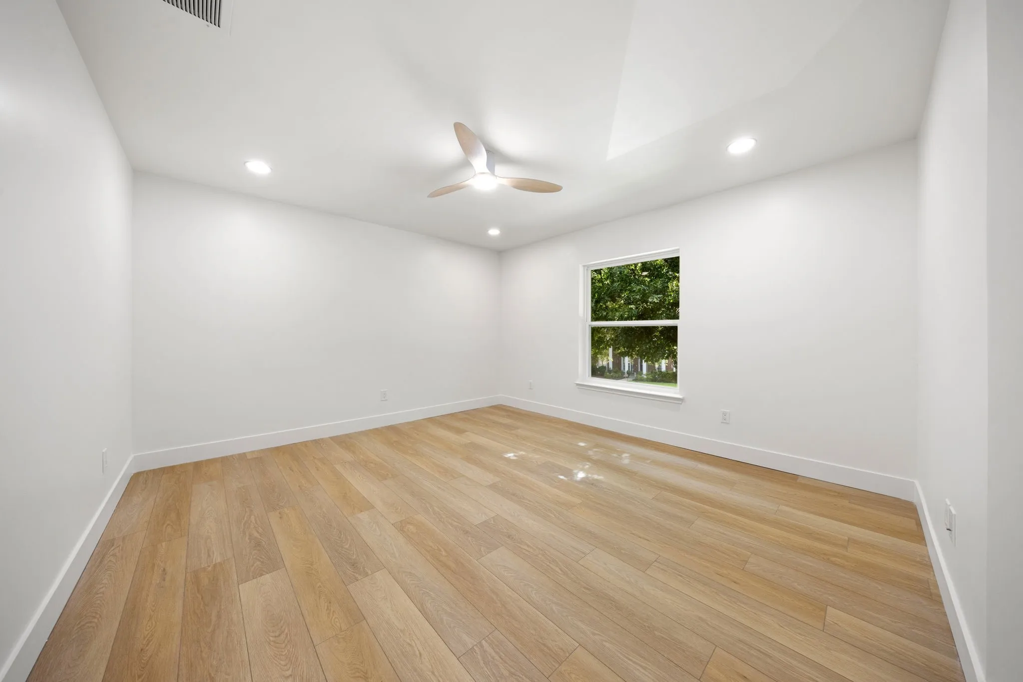 Bright room featuring wood-finish flooring, a contemporary ceiling fan, recessed lighting, a single window, and a vaulted ceiling