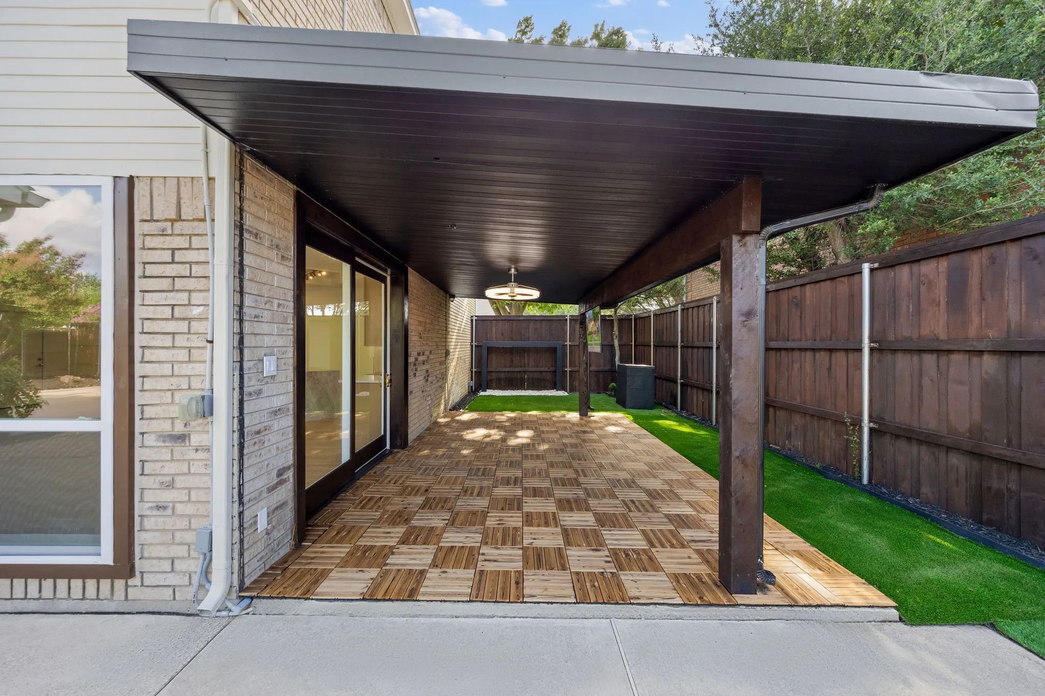 Expansive covered patio featuring a checkered wood-finish floor and overhead lighting