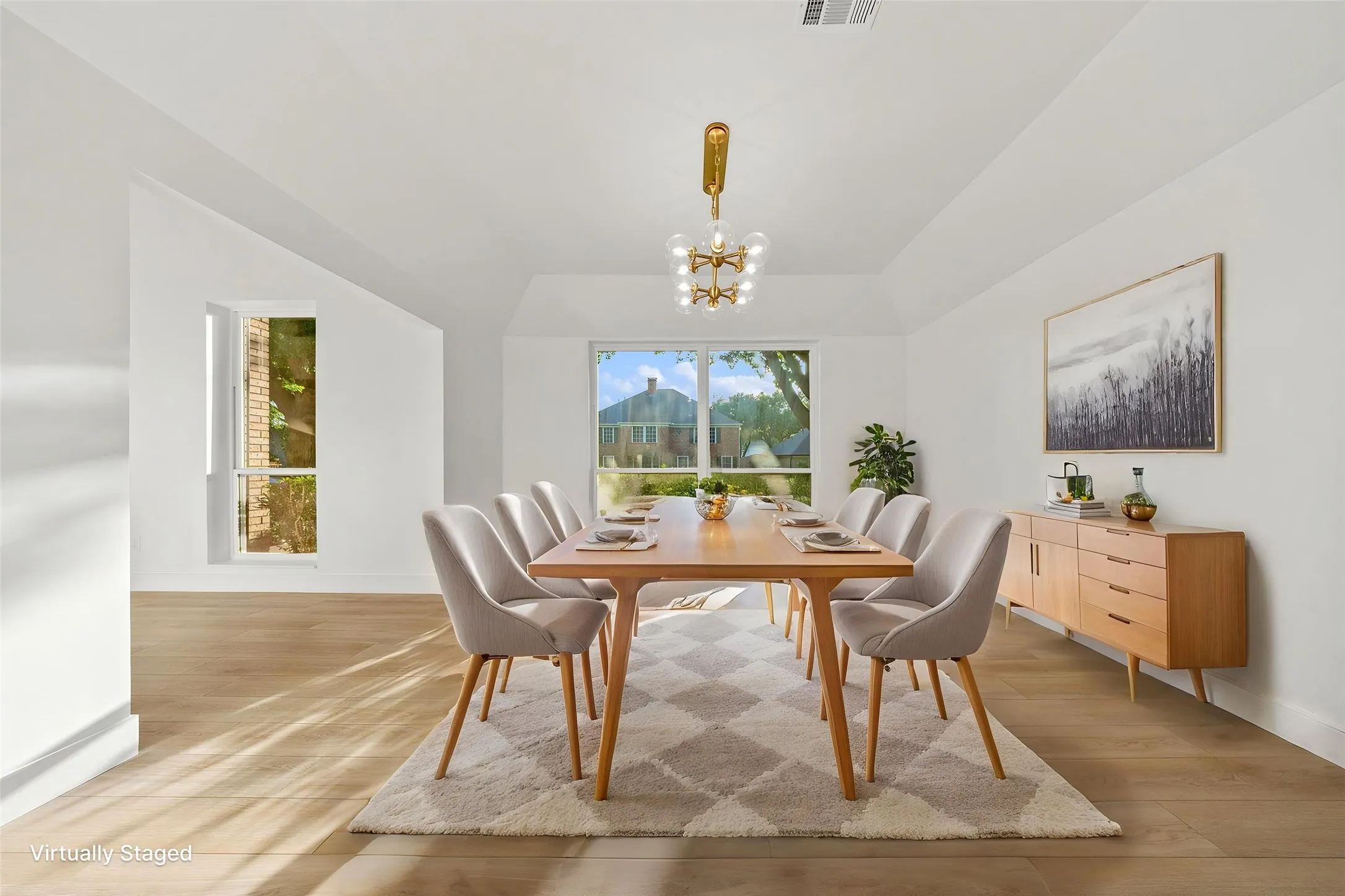 Dining area featuring wood-finish flooring, vaulted ceiling, and a prominent window