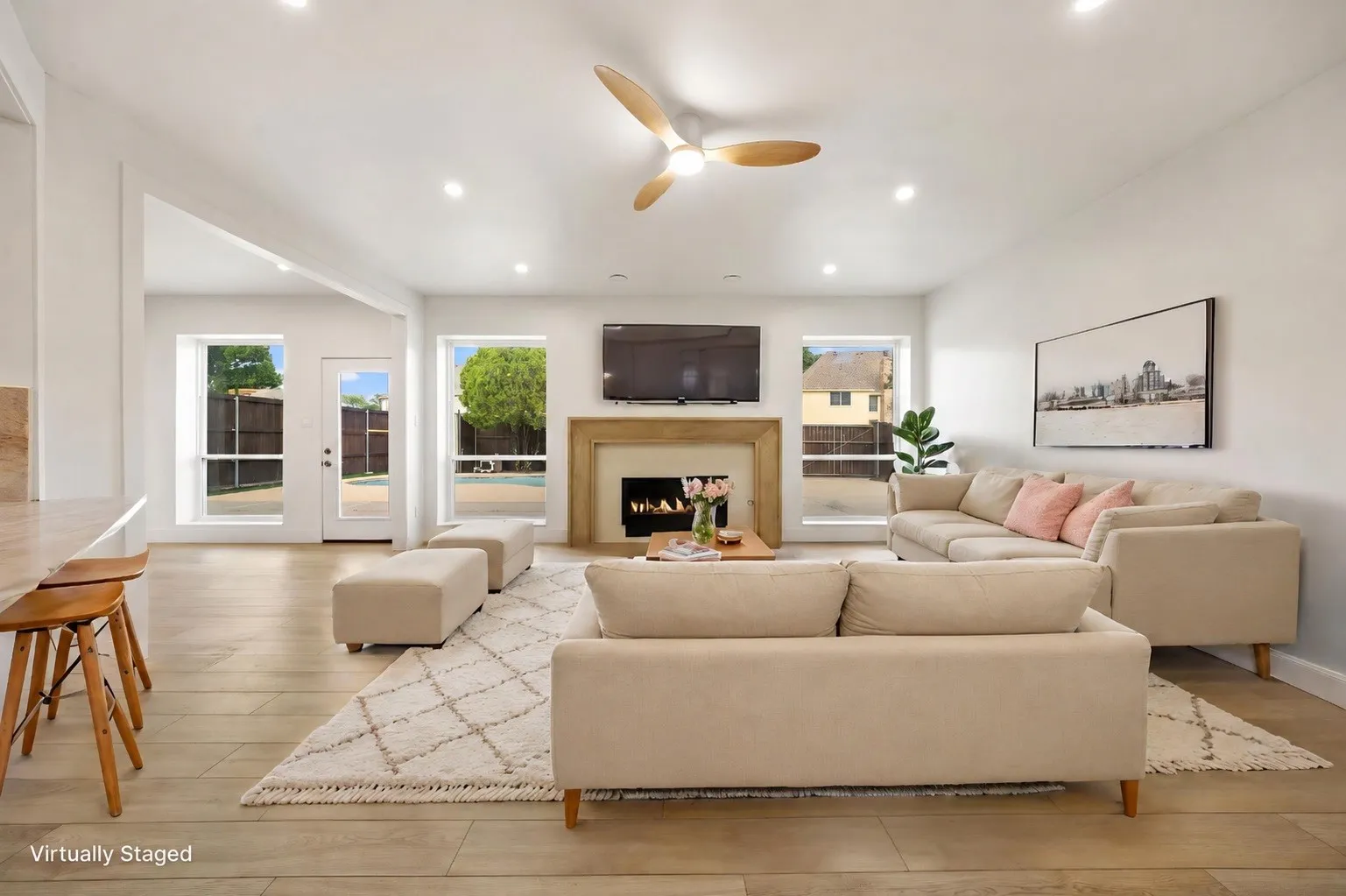 Spacious living area featuring a fireplace with a stone surround, recessed lighting, wood-finish flooring, and a contemporary ceiling fan