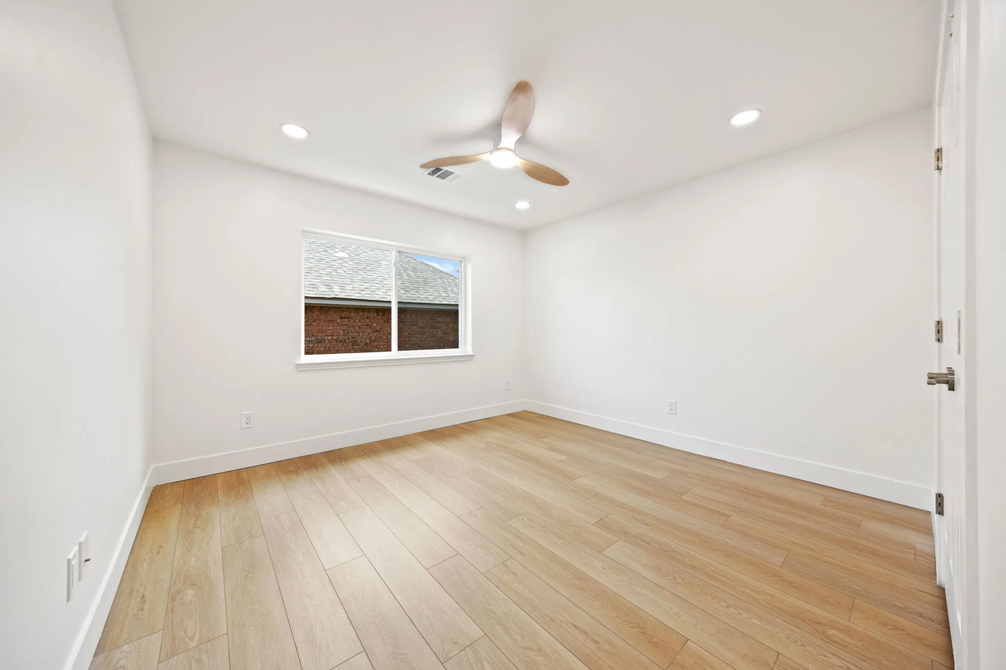 Bright interior space featuring light wood-finish flooring, white walls, and a recessed lighting package