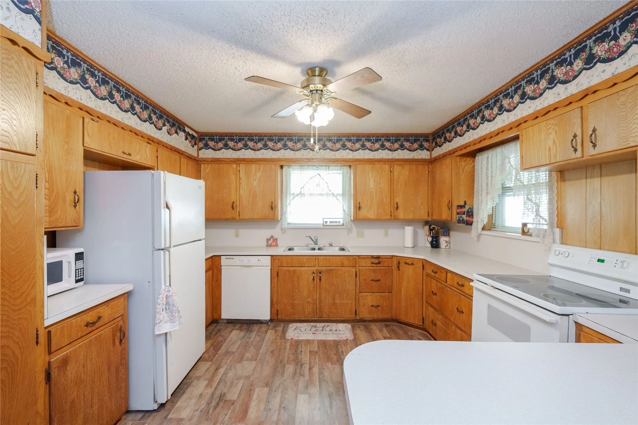 Kitchen featuring wood-finish cabinetry, white countertops, a ceiling fan, and wood-finish flooring