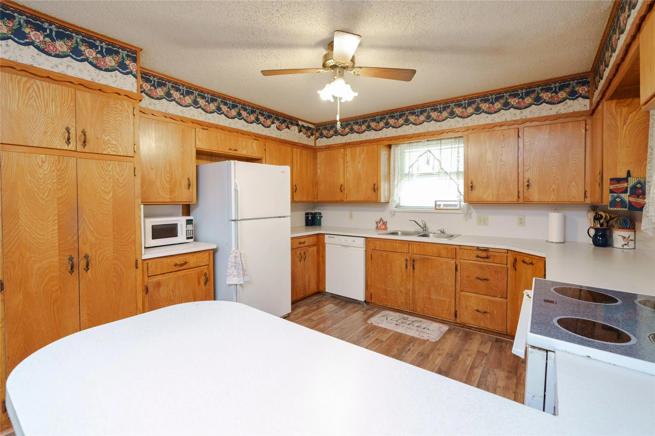 Wood-finish cabinetry throughout with white countertops, complete with a double-basin stainless steel sink