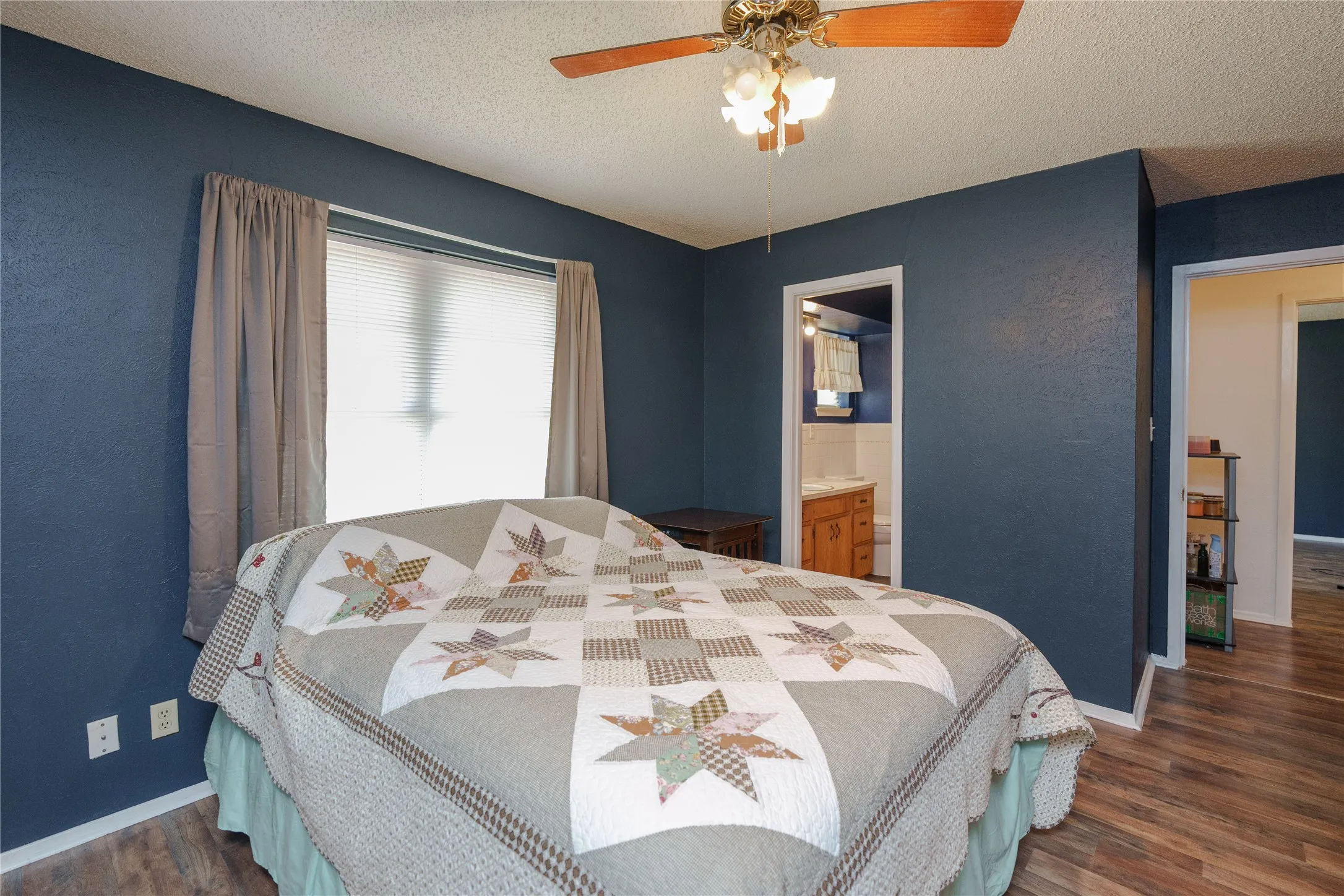 Wood-finish flooring, ceiling fan with integrated lighting, window with blinds, and blue painted walls