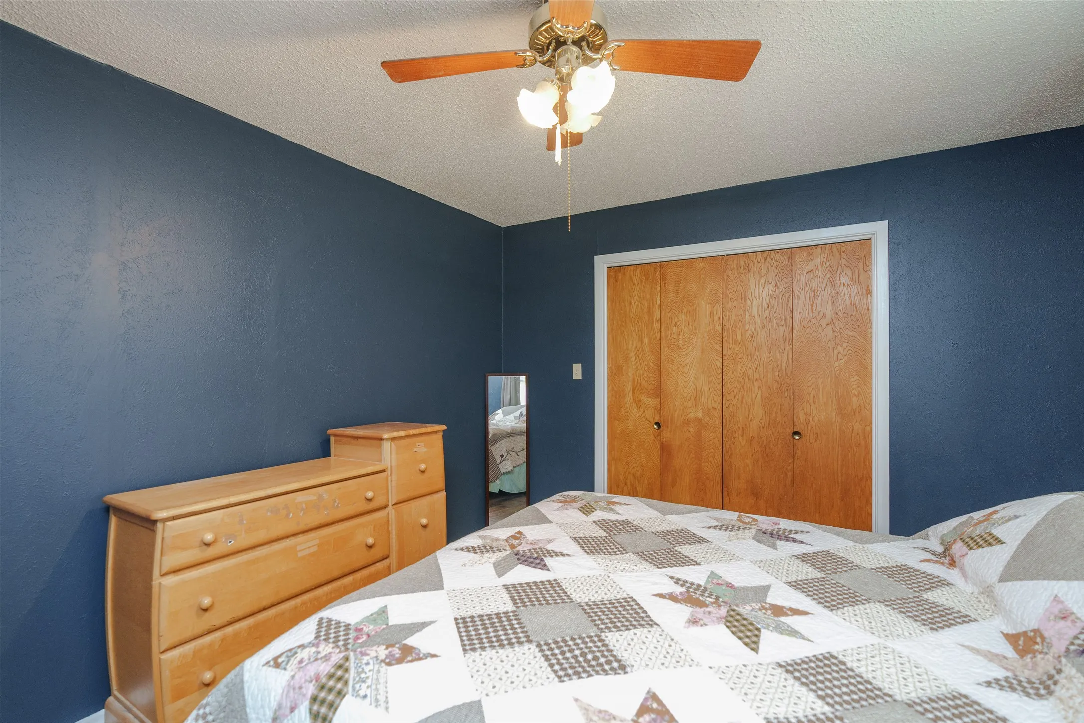 Built-in closet with wood-finish bi-fold doors, white trim, and a ceiling fan with integrated lighting