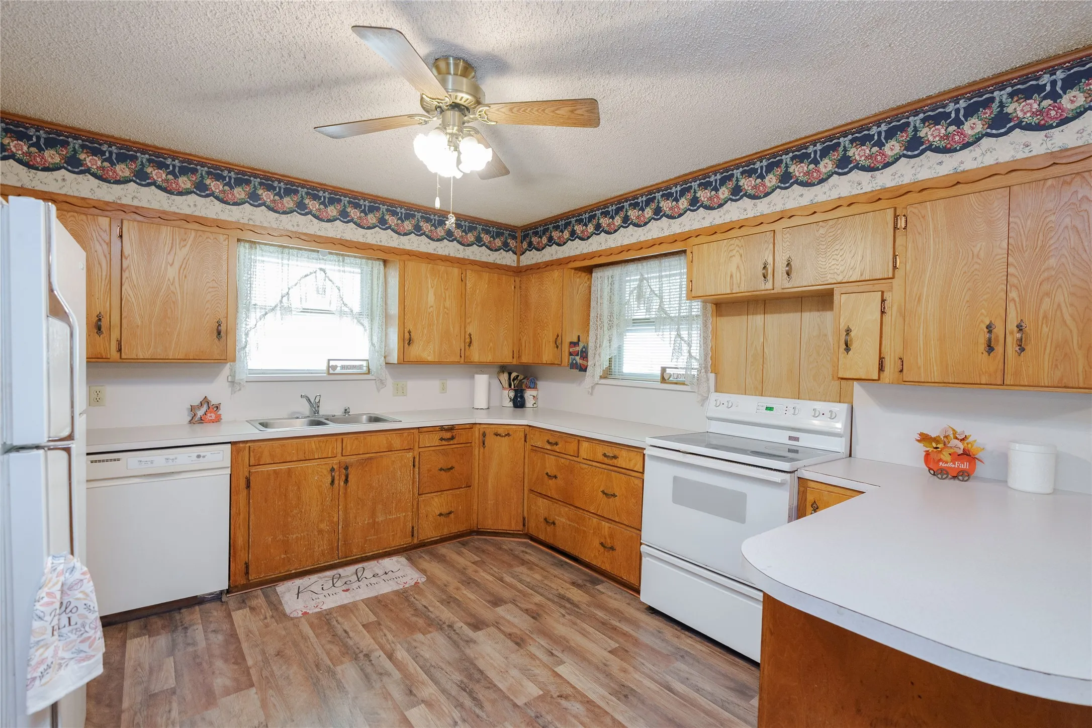Kitchen with wood-finish flooring, wood cabinetry, white countertops, and white appliances